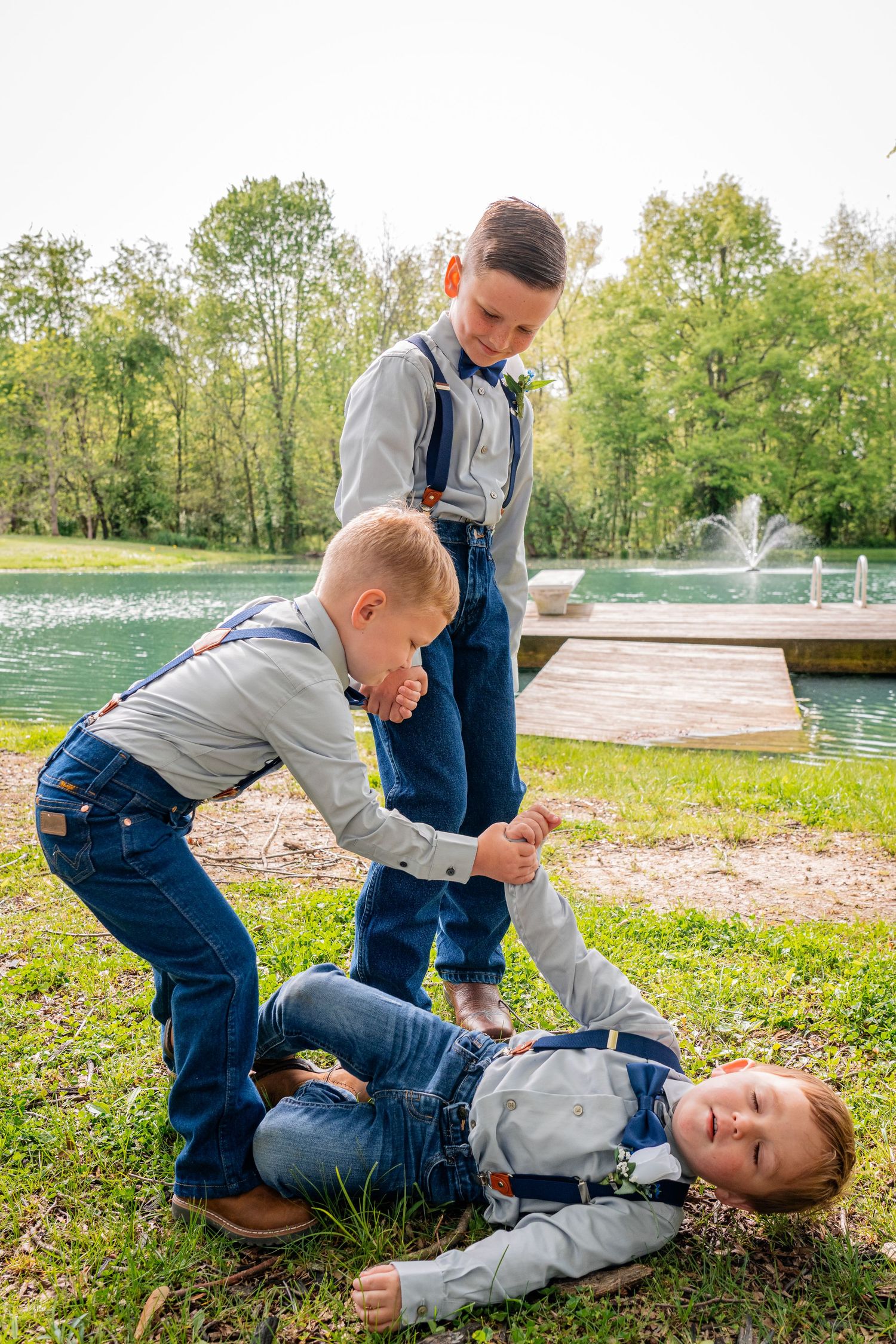 Playful scene of children in formal wear playing on grass near fountain.