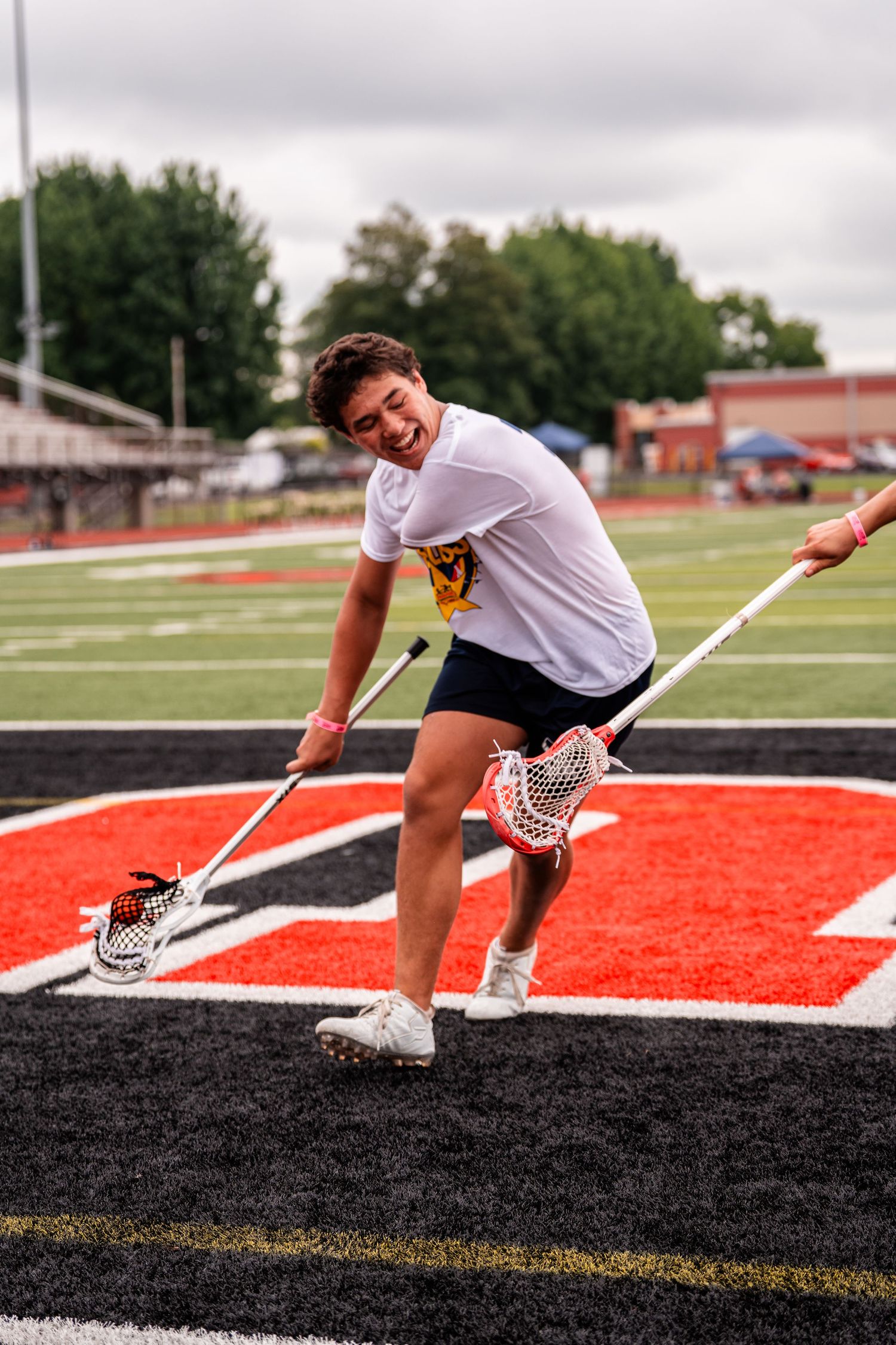 Athletes demonstrate dynamic stretching exercises on a red and black athletic field surface.