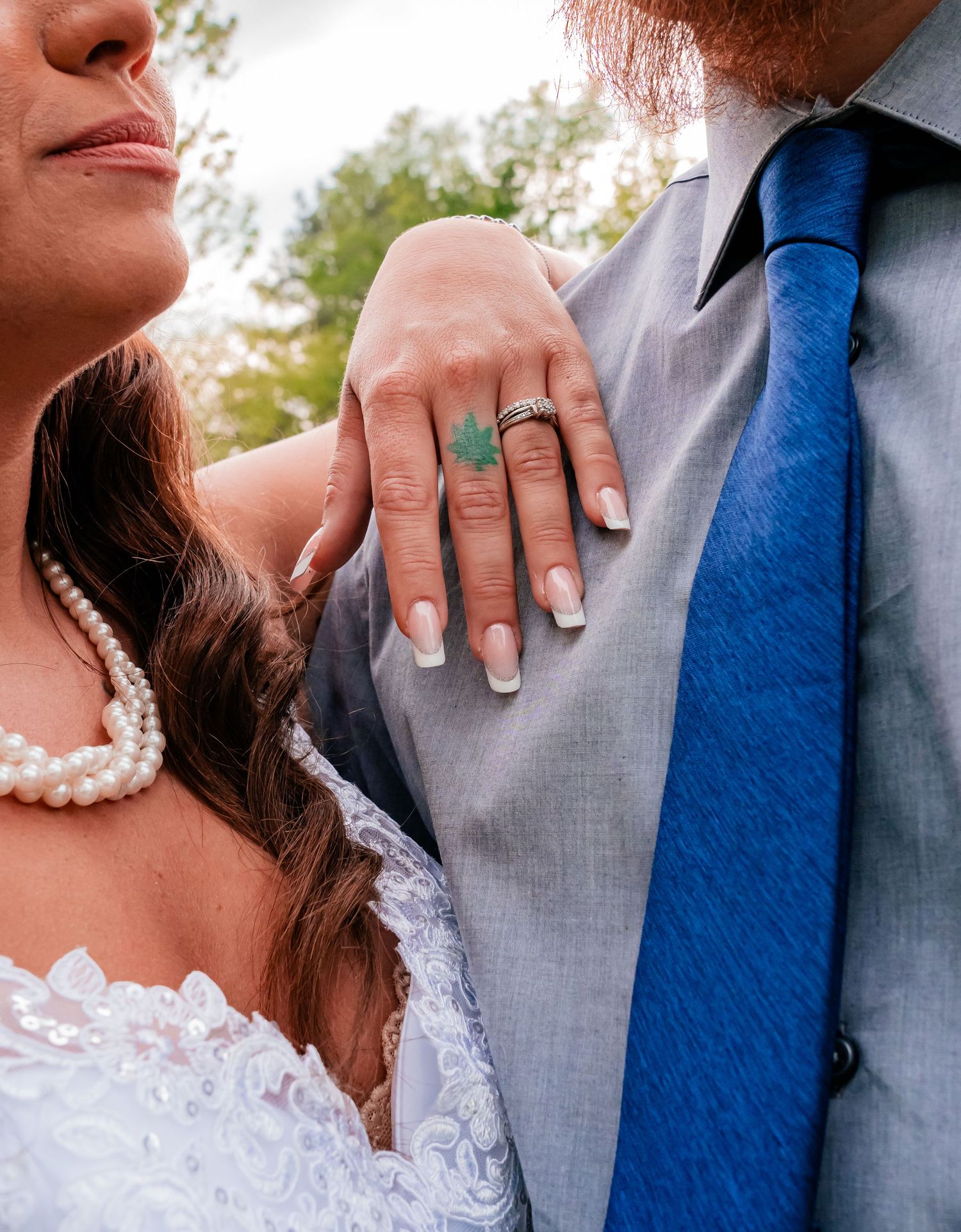 Close-up of bride's hand with turquoise ring resting on groom's grey suit.