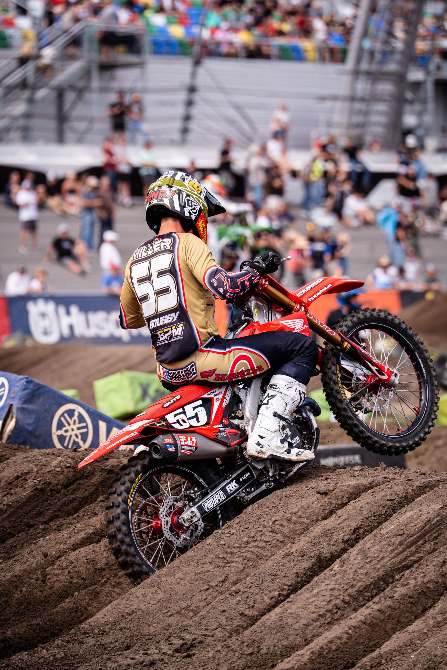 Motocross riders racing over dirt jumps during professional competition event.