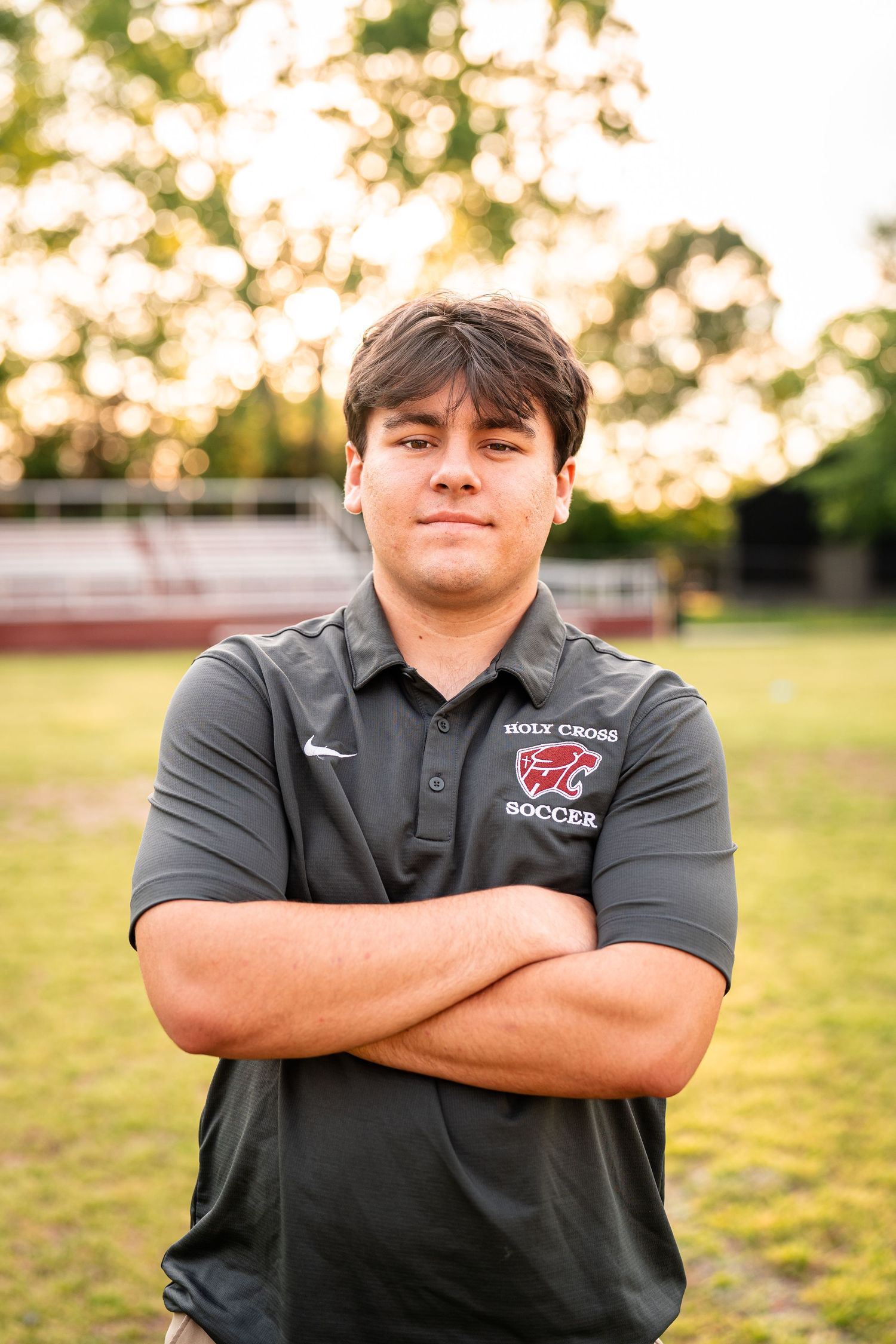 Student athlete in Holy Cross polo shirt poses for portrait outdoors.