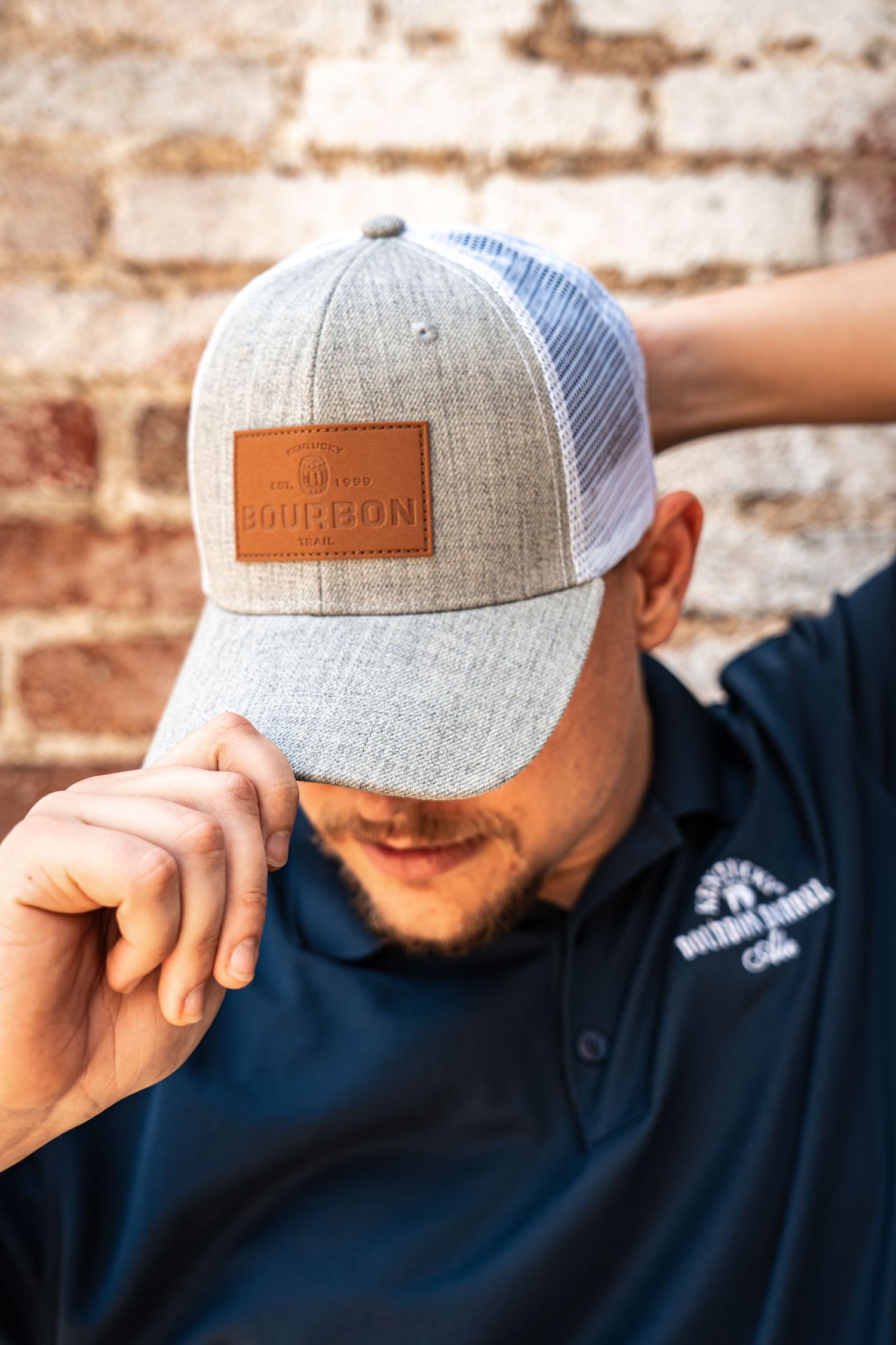Grey mesh trucker hat with leather bourbon company logo patch.