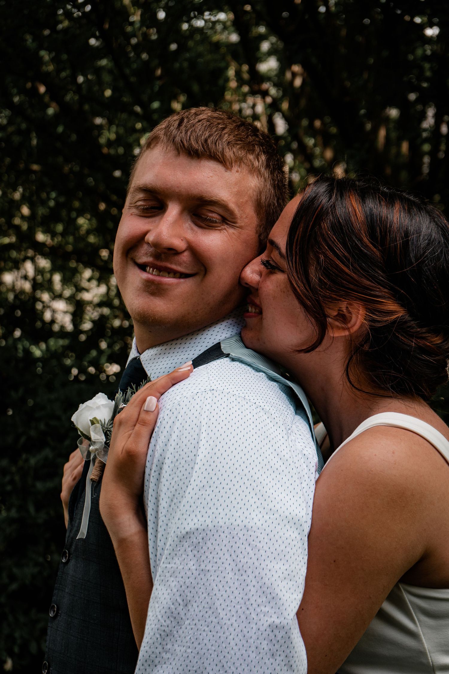 Tender candid moment between newlyweds sharing joy outdoors.
