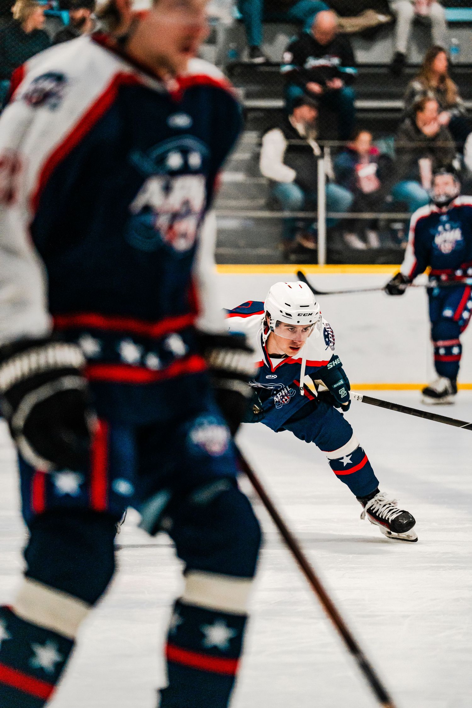 Hockey players in blue and white uniforms skating on ice during an intense game.