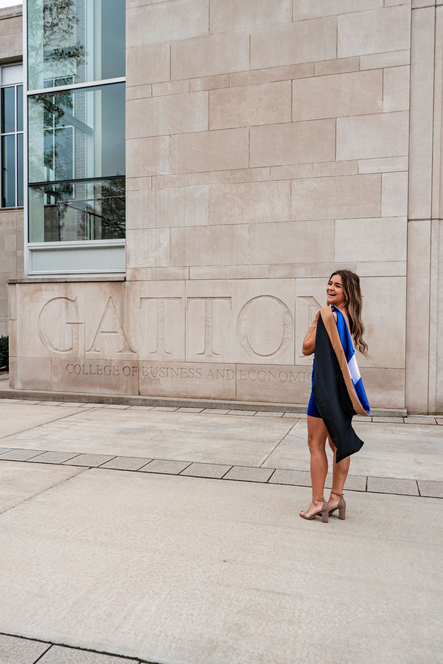 Graduate in cap and gown poses against stone wall in artistic photo sequence.
