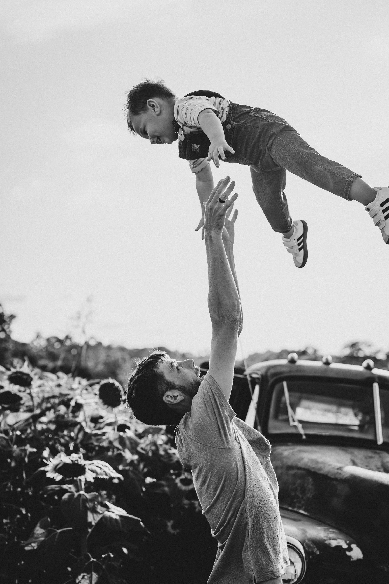 Black and white photo of playful moments in a sunflower field at sunset.