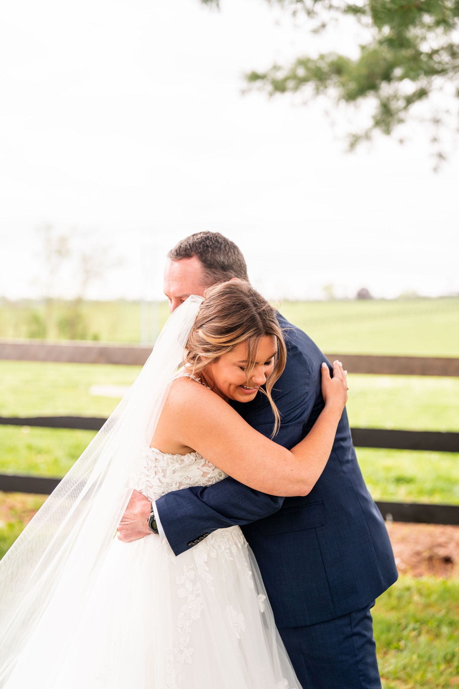 Tender embrace between wedding couple on a countryside farm.