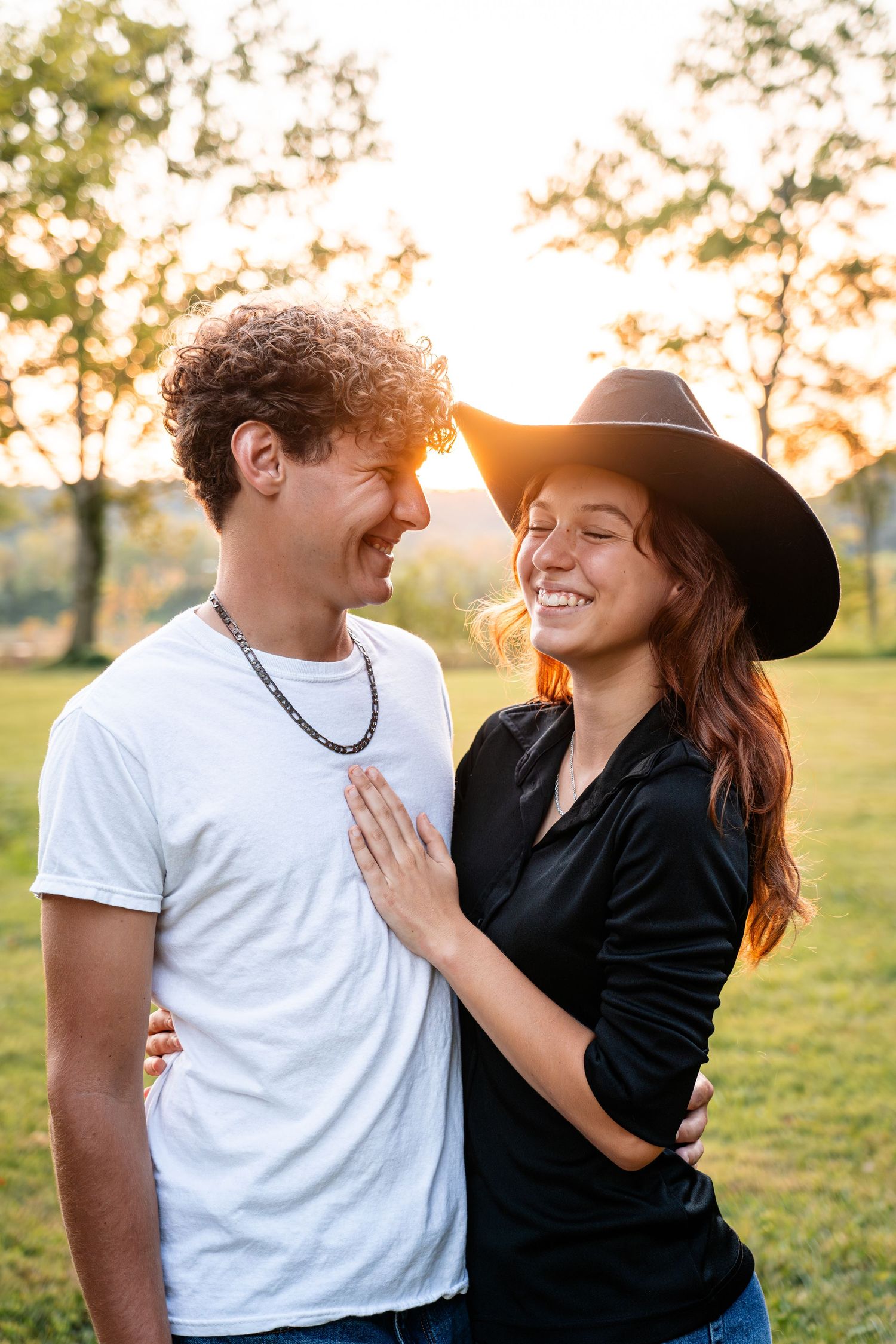 Romantic couple sharing tender moments at golden hour in a grassy field.