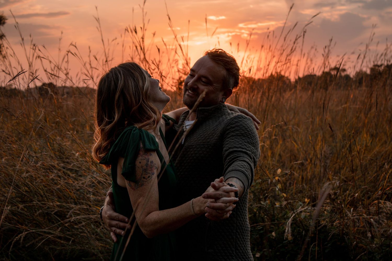 couple dancing in a prairie during sunset