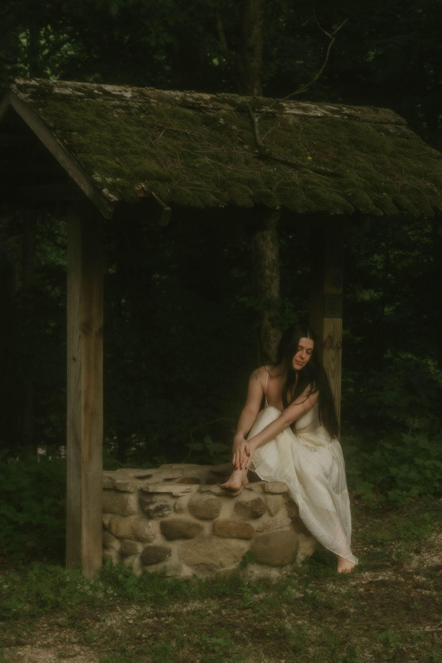 woman in white dress sitting at a vintage well