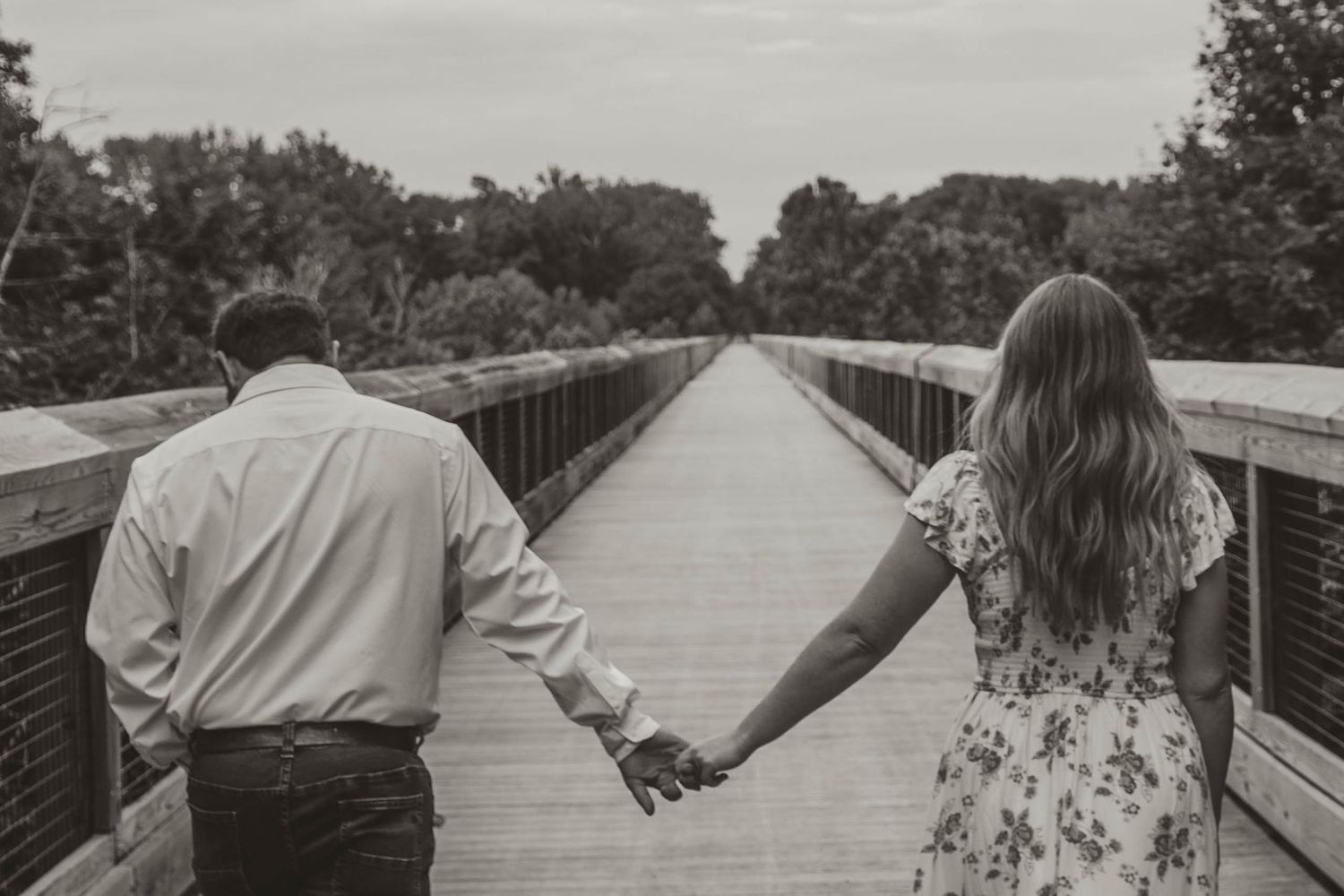 couple walking and holding hands while walking down Kickapoo rail trail bridge