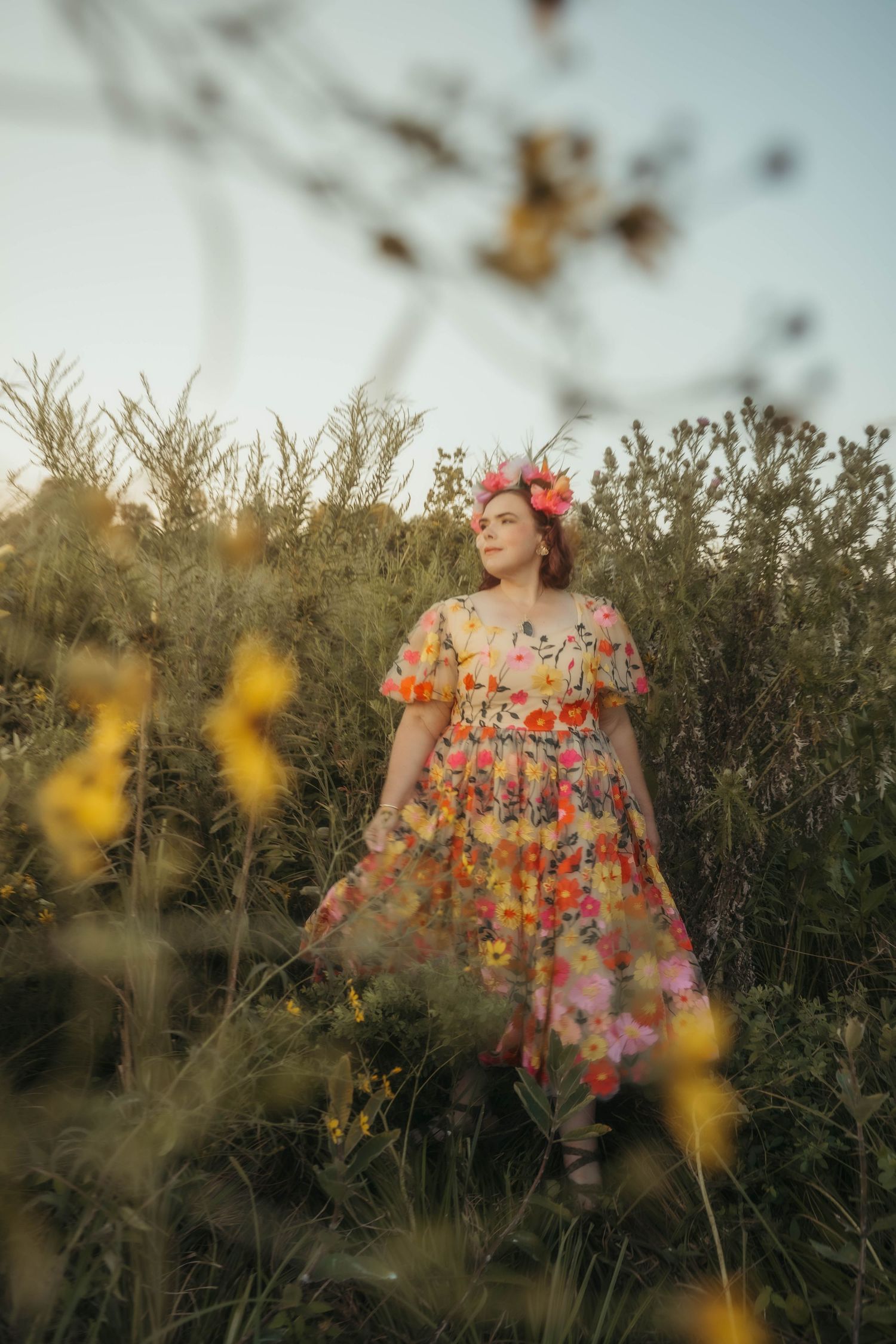 Woman in floral gown dancing in a wildflower field