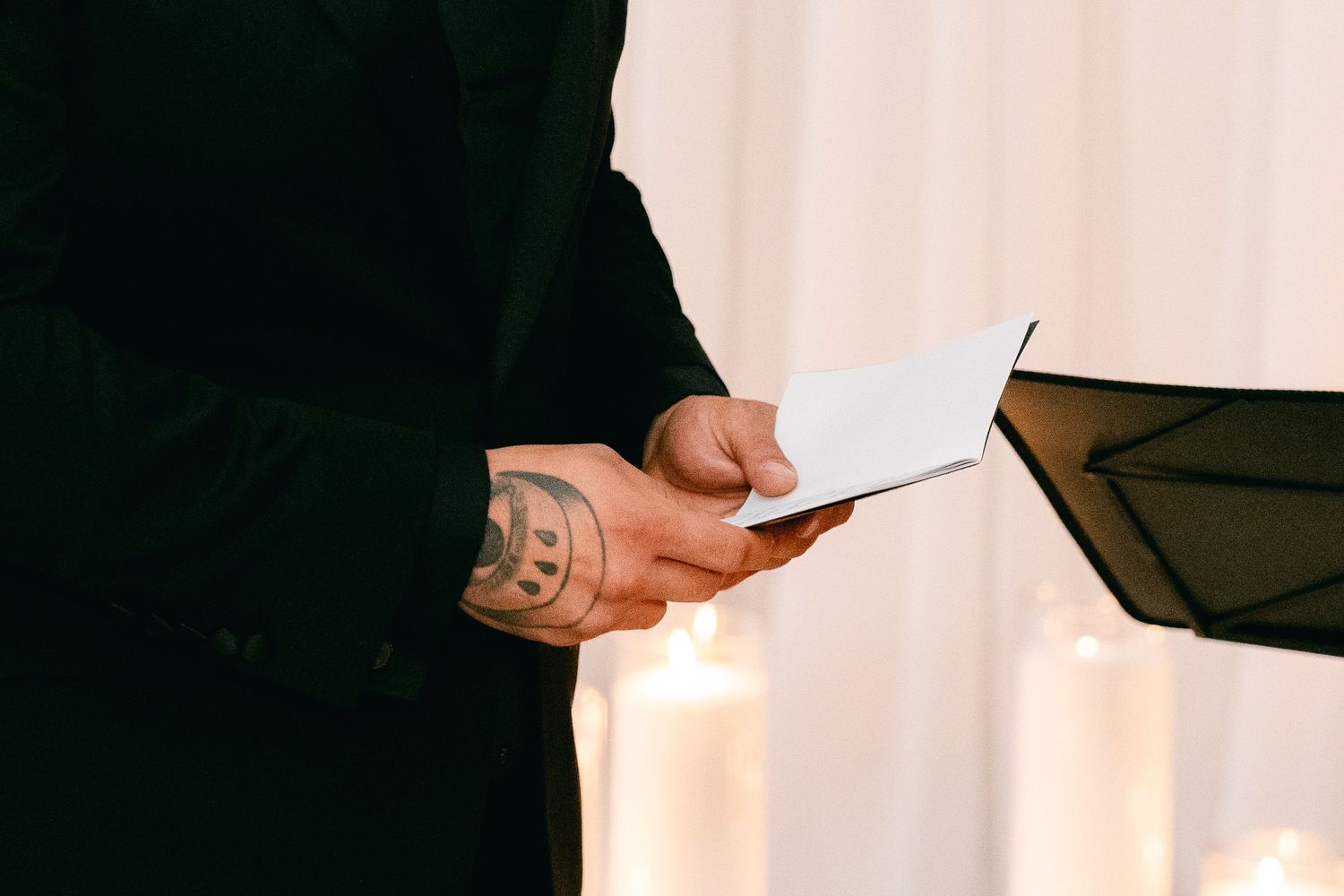 Hands hold wedding ceremony papers during candlelit service.