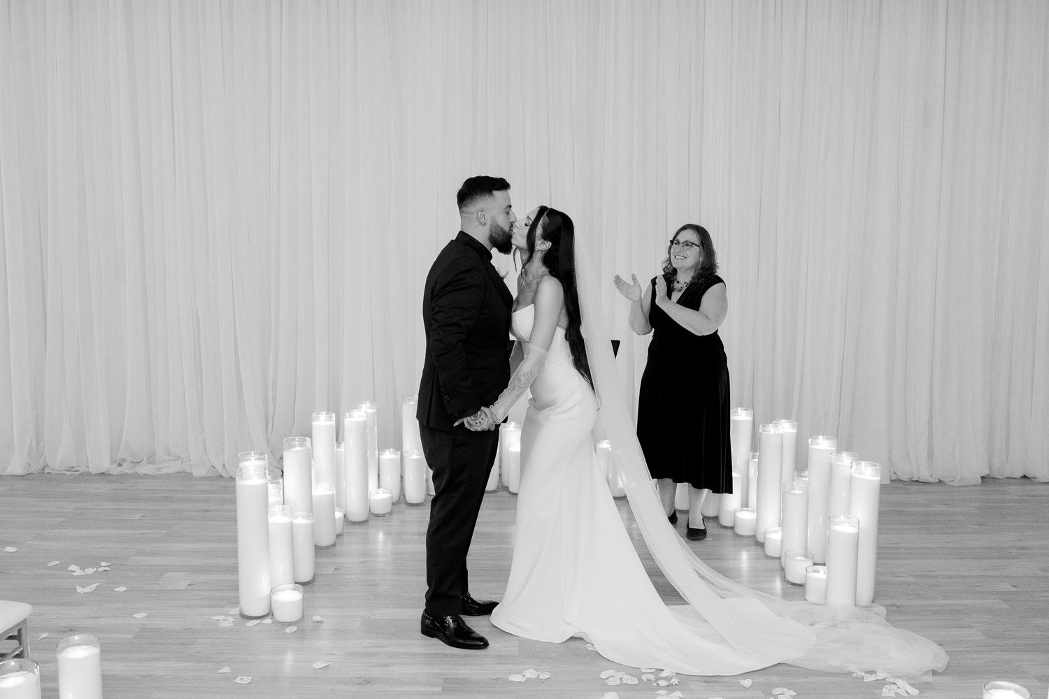 Intimate wedding ceremony with glowing candles and white backdrop.