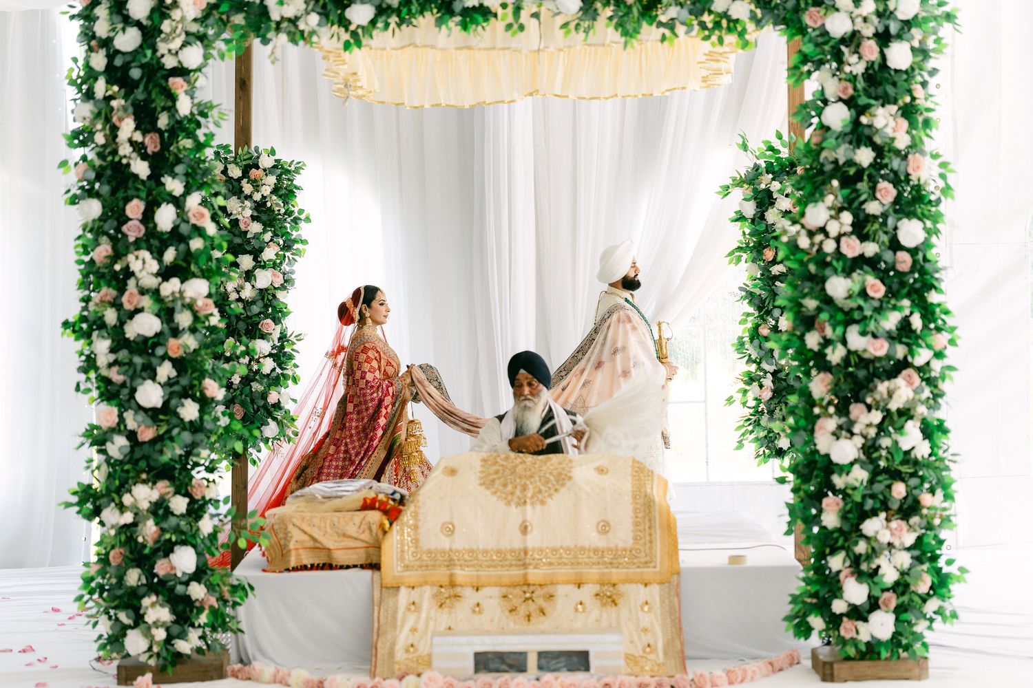 Elegant wedding decor with floral archways and white chairs arranged for an indoor ceremony.