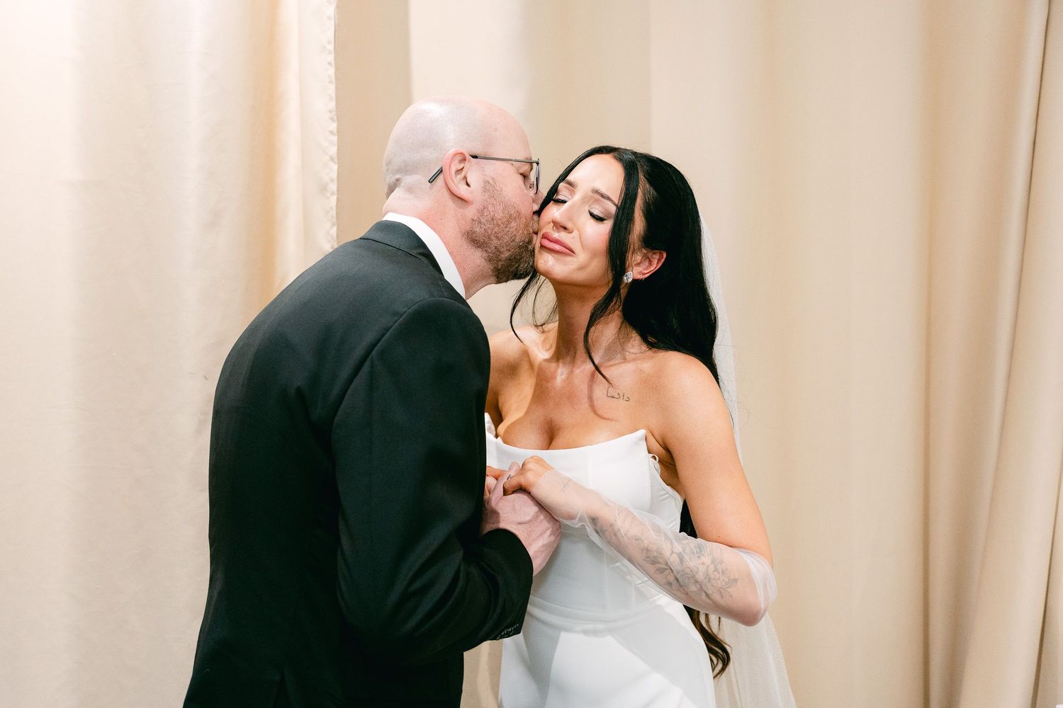 A tender moment shared between someone in a traditional dress stifling laughter and another person in formal attire.