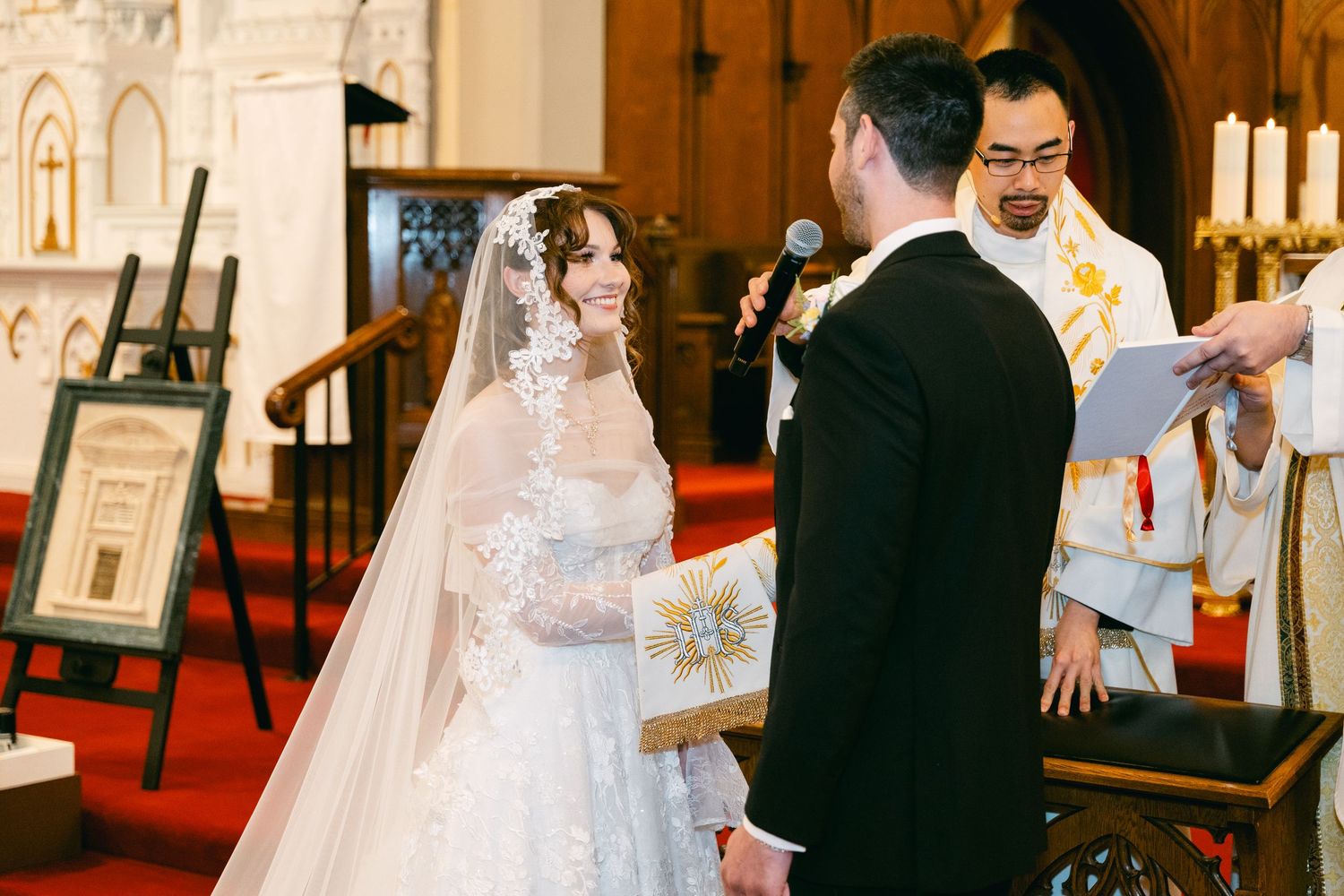 Bride and groom exchanging vows at a church altar during a traditional wedding ceremony with a priest officiating.