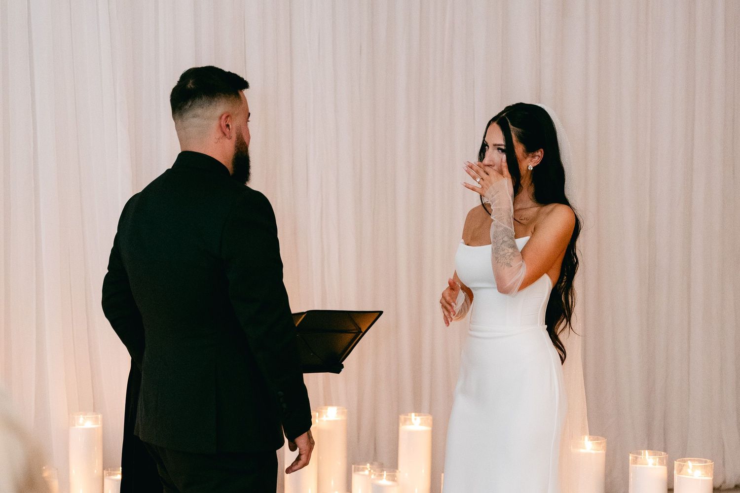 Emotional wedding ceremony moment as couple reads vows surrounded by candlelight.