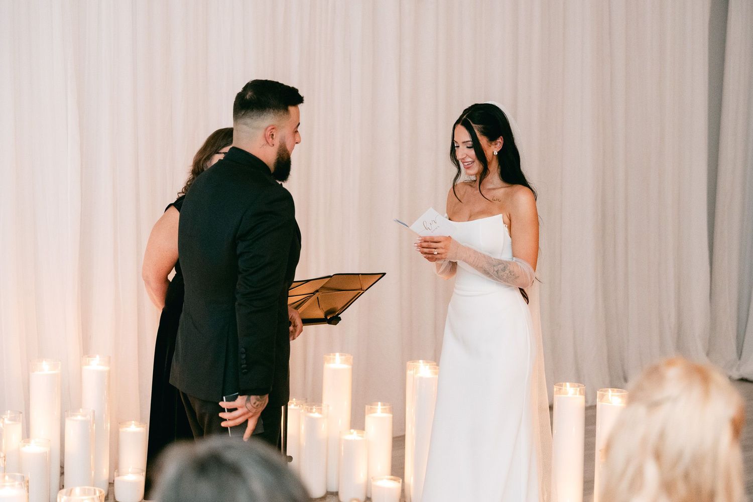 Couple shares personal wedding vows surrounded by glowing candles.