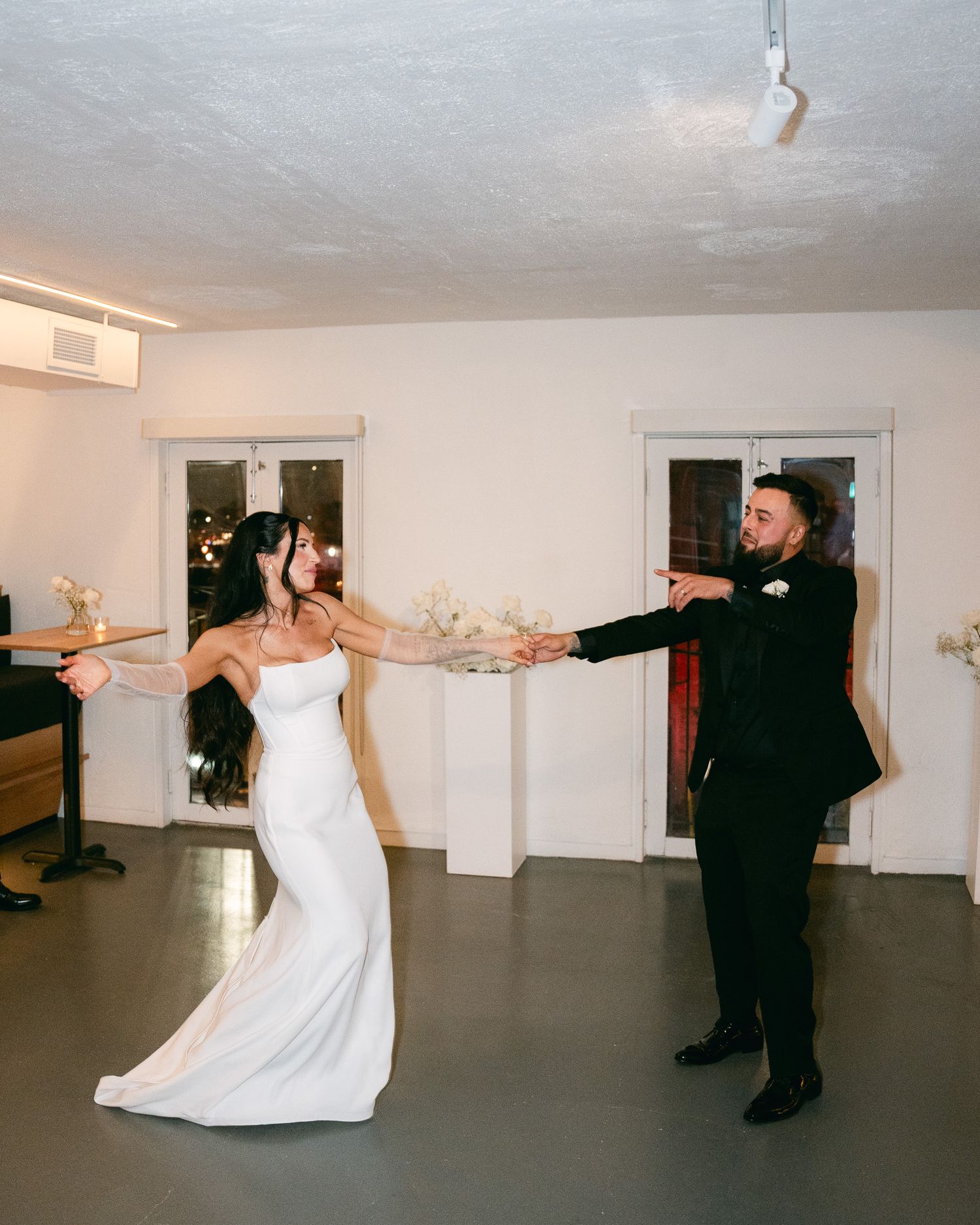 A playful dancing moment between newlyweds in a minimalist reception space.