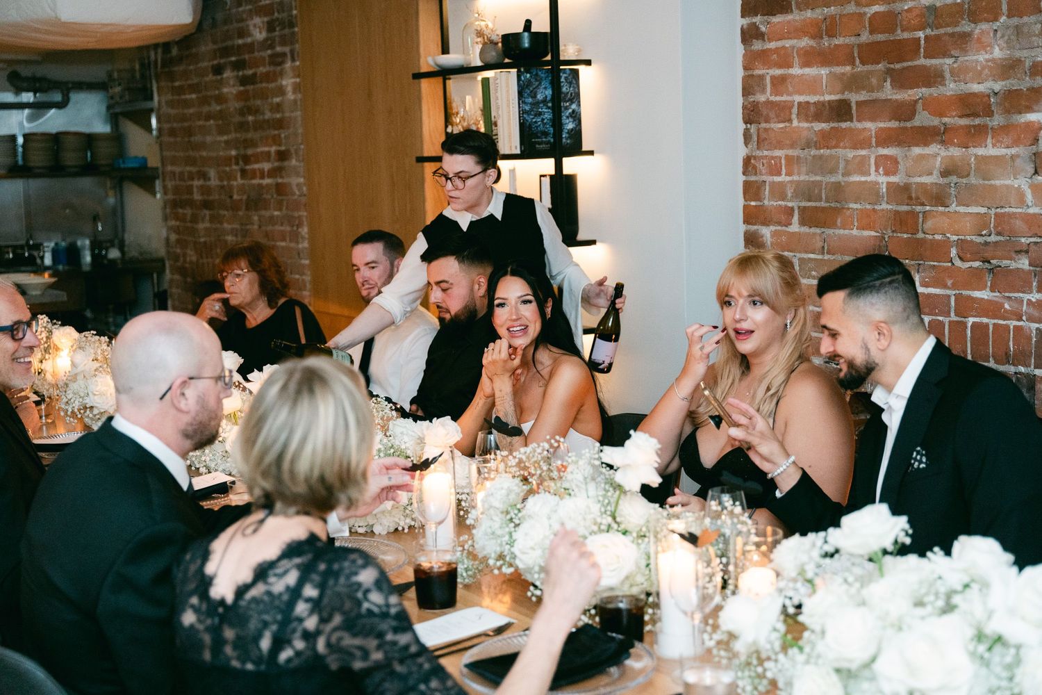 Wedding reception dinner featuring elegant table settings against exposed brick walls.