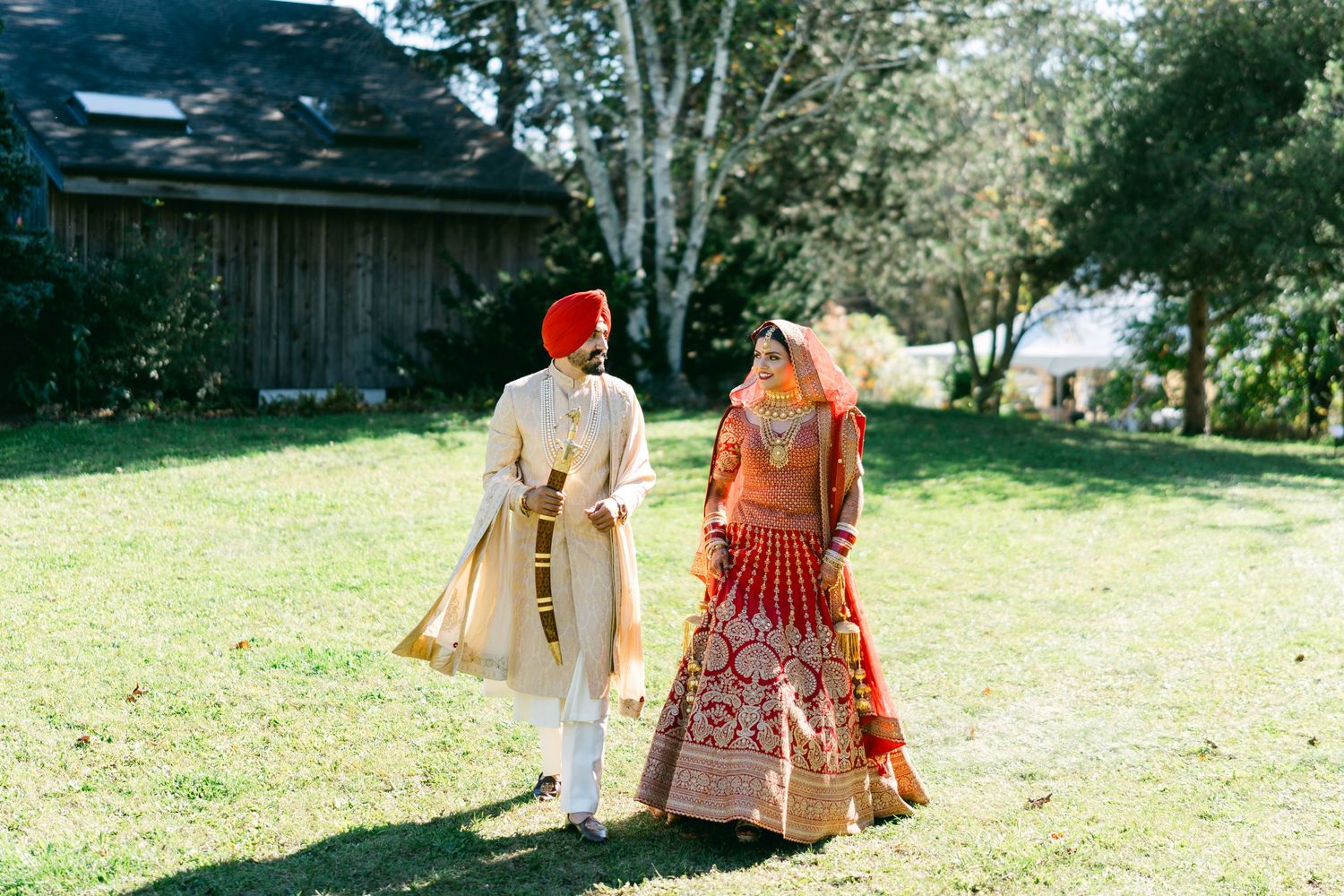 Wedding guests in bright traditional attire walking on a grassy path outdoors.