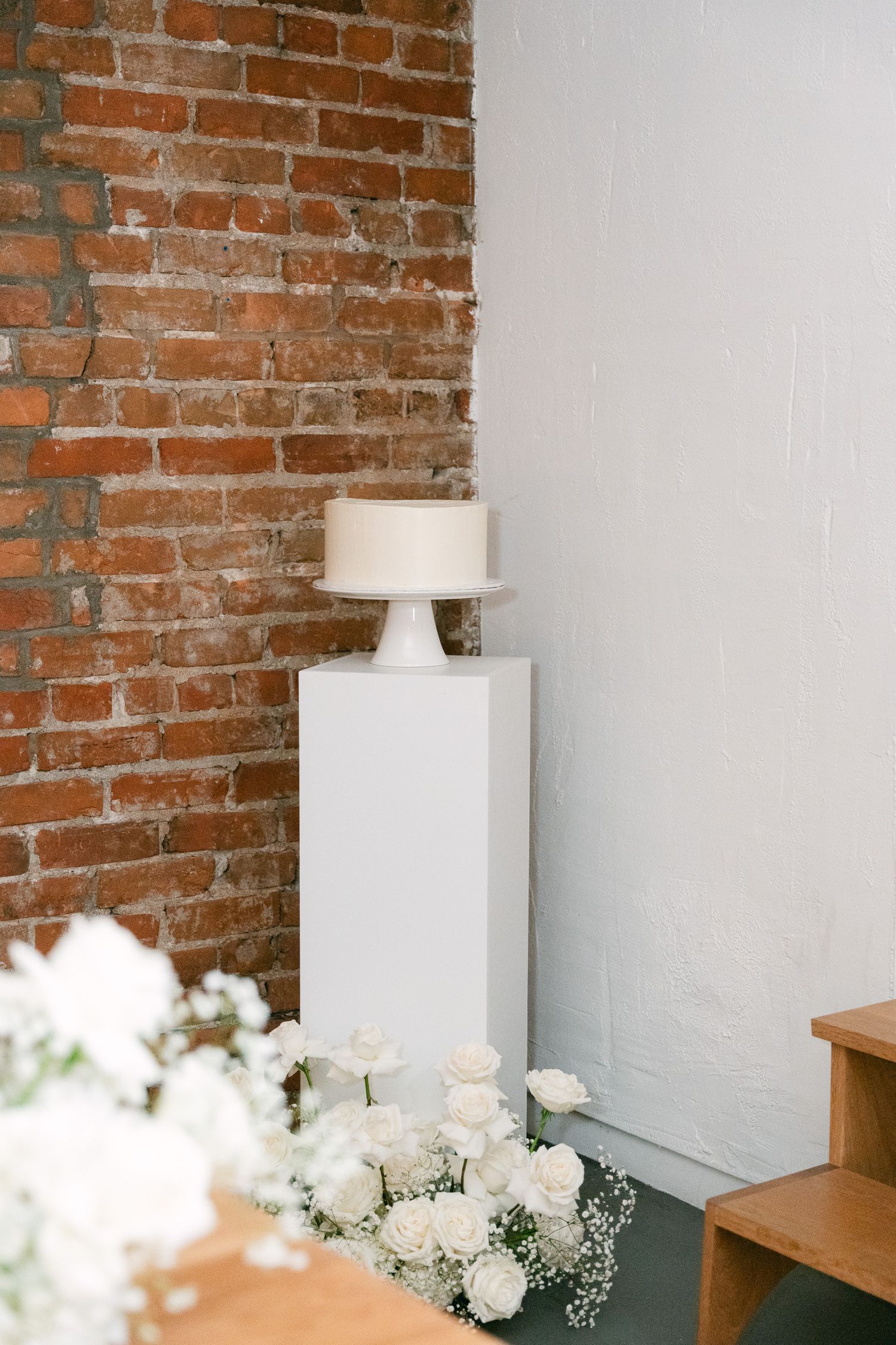 Modern wedding venue interior with exposed brick wall and white floral arrangements.