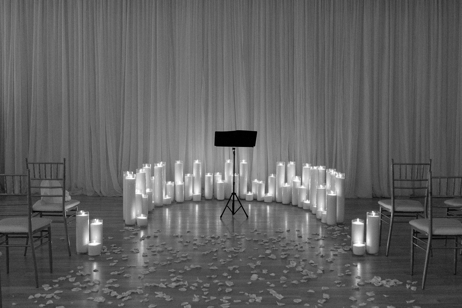 Wedding venue decorated with glowing candles and elegant white drapery.