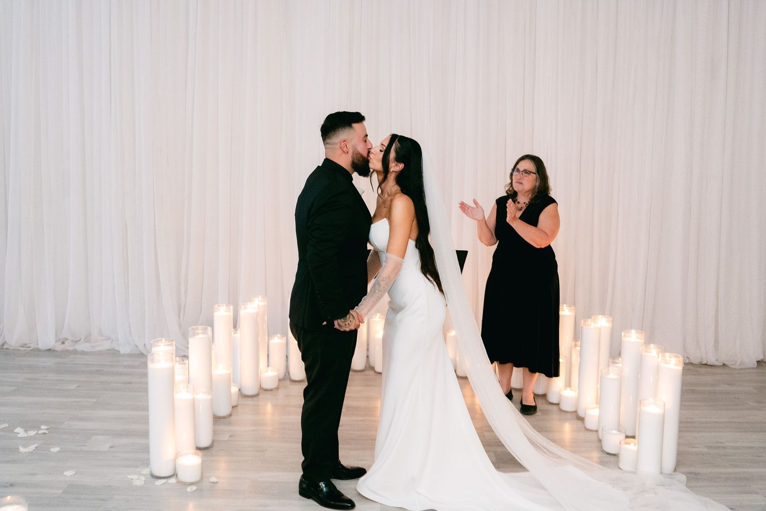 Wedding ceremony setting with lit candles and white drapery.