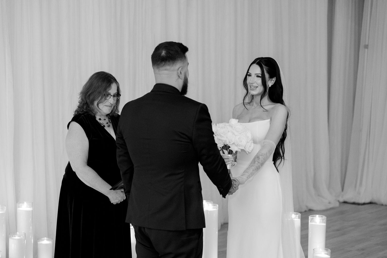 Wedding ceremony guests share heartfelt moments in a bright white venue.