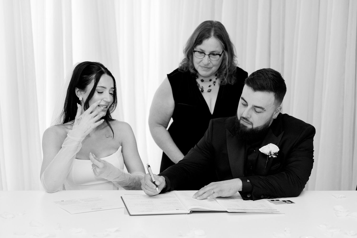 People seated at a wedding ceremony during document signing.