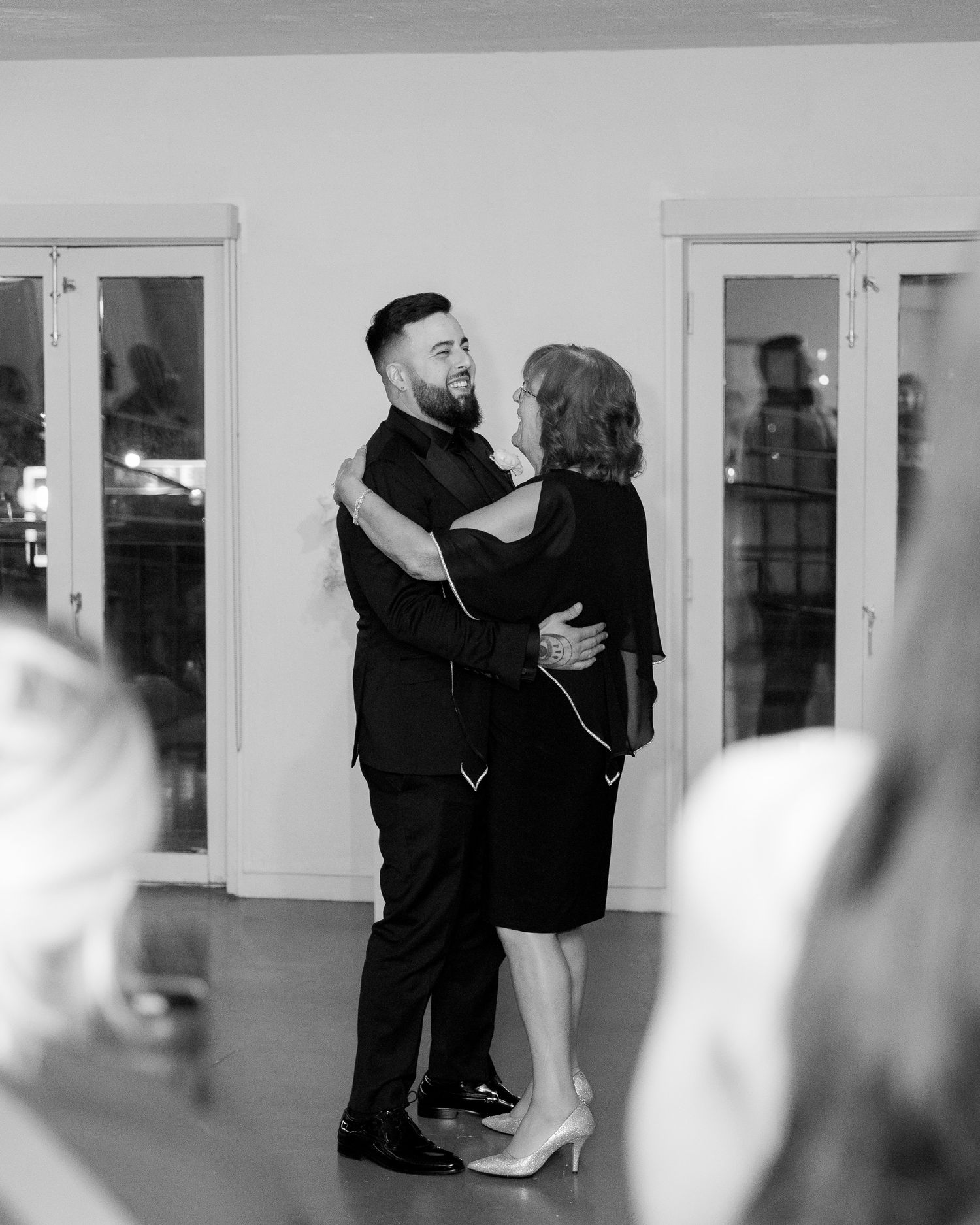A black and white photo showing couples dancing together in a spacious indoor venue.