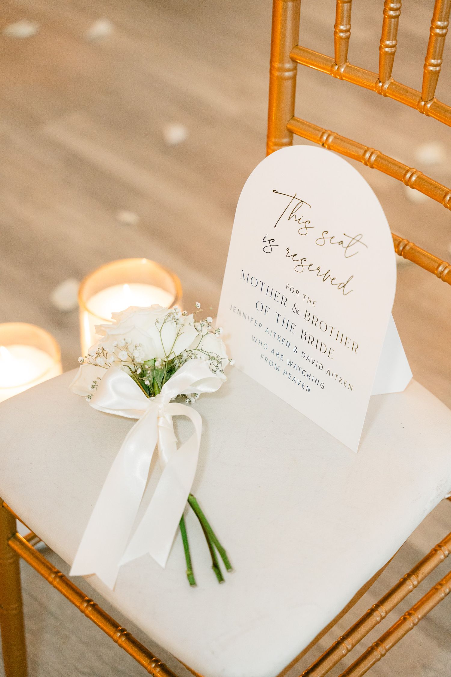 White wedding place cards and floral arrangements on wooden Chiavari chairs.