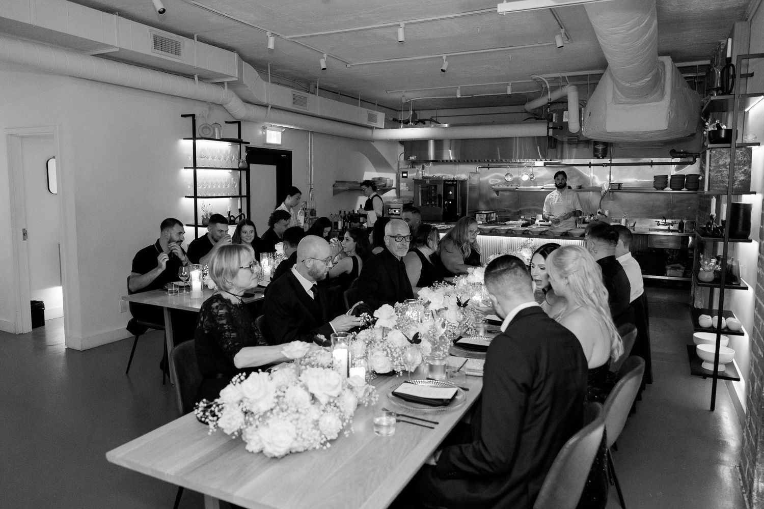 Wedding reception panorama showing tables, floral arrangements and guests in an elegant modern space.