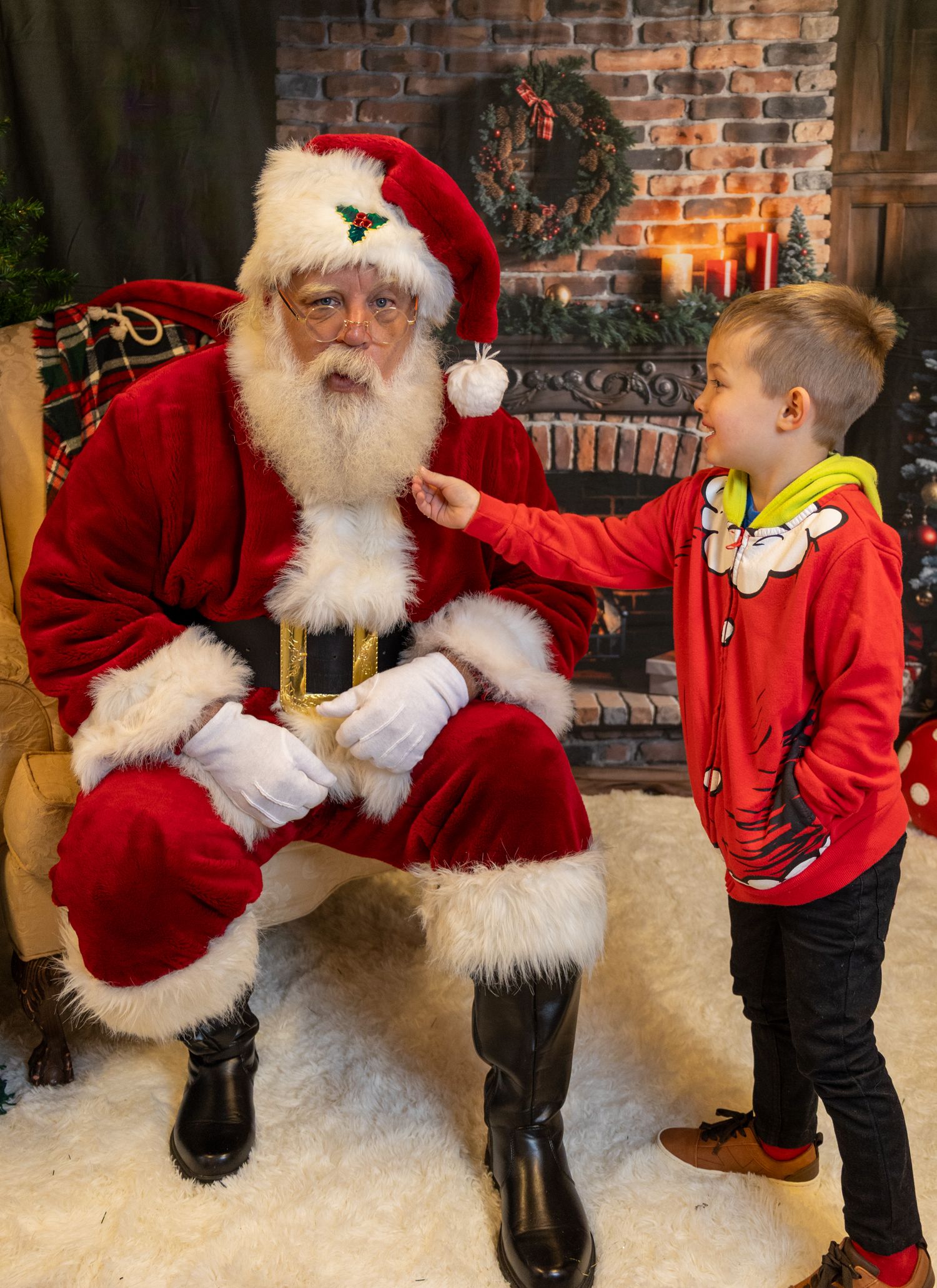 A sequence of playful interactions between Santa Claus in his red suit and a small child in front of a brick fireplace.