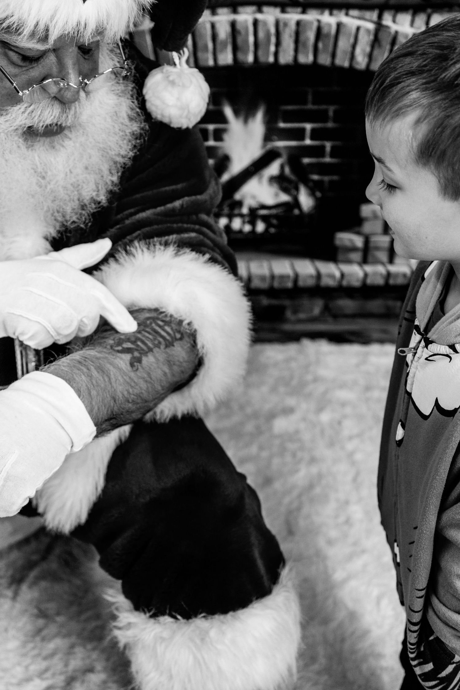 Black and white image of someone petting a fluffy white dog with Christmas decorations in the background.
