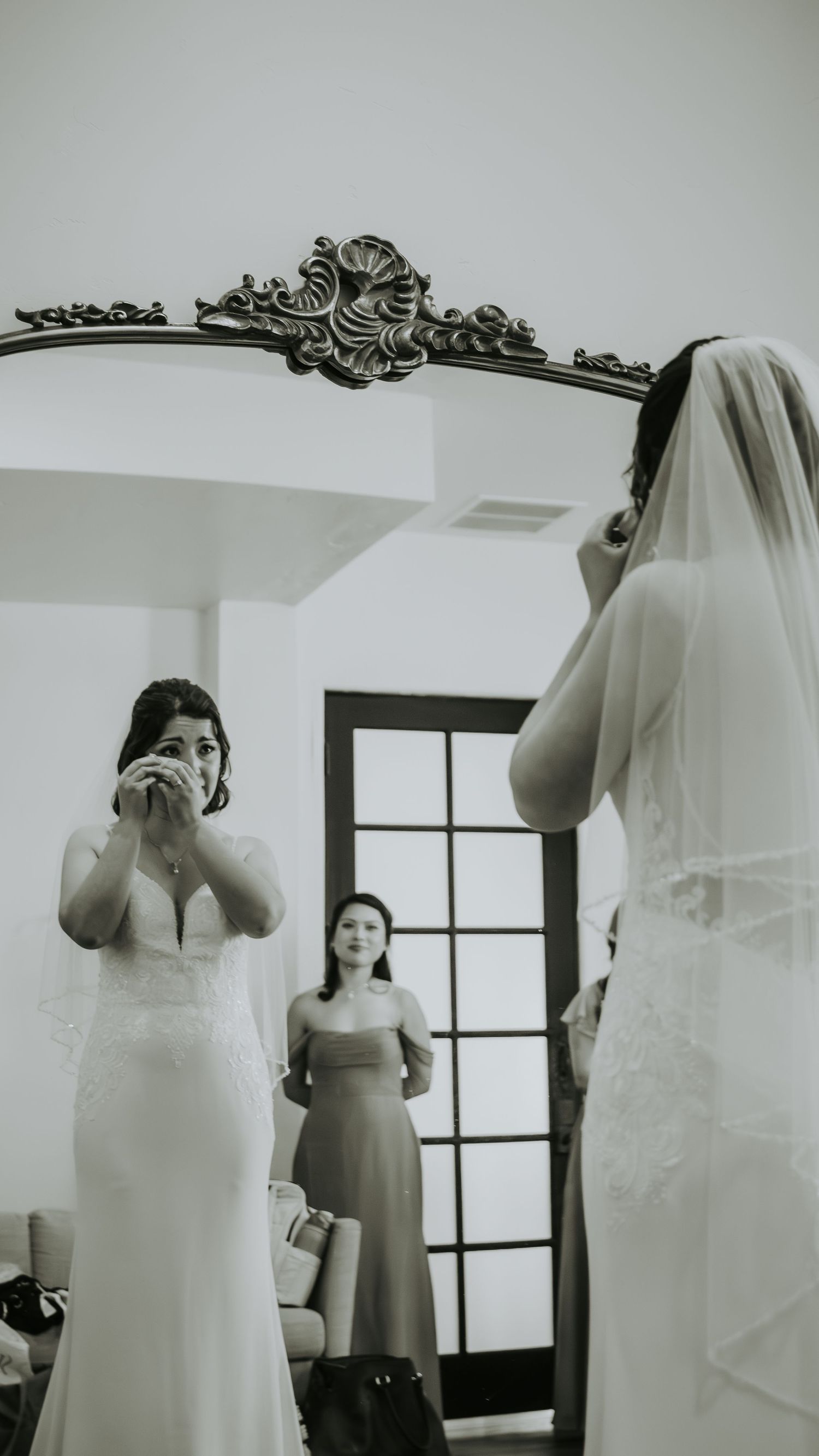 Black and white wedding preparation photos showing emotional moments during dress fitting.