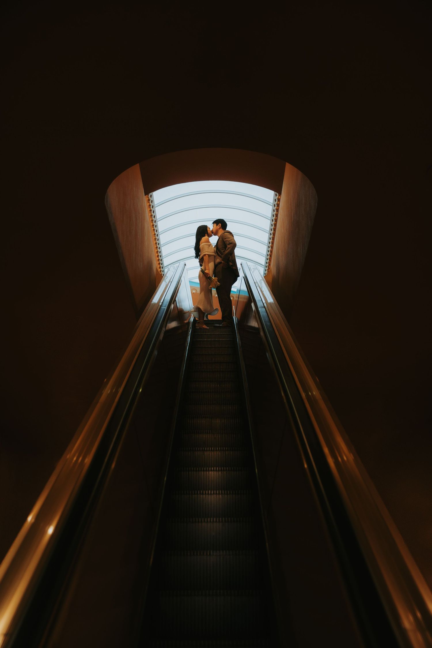 A dramatic sequence of silhouettes on an illuminated escalator in a dark environment.