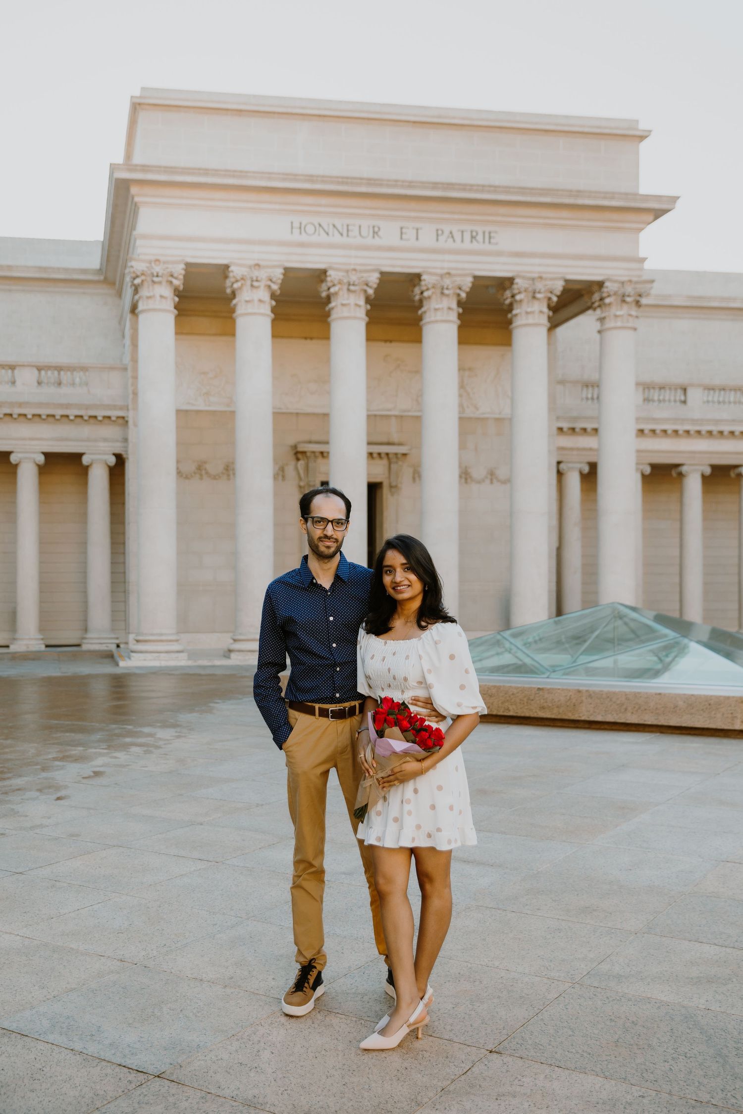 A couple poses together for engagement photos in front of the Legion of Honor museum in San Francisco.