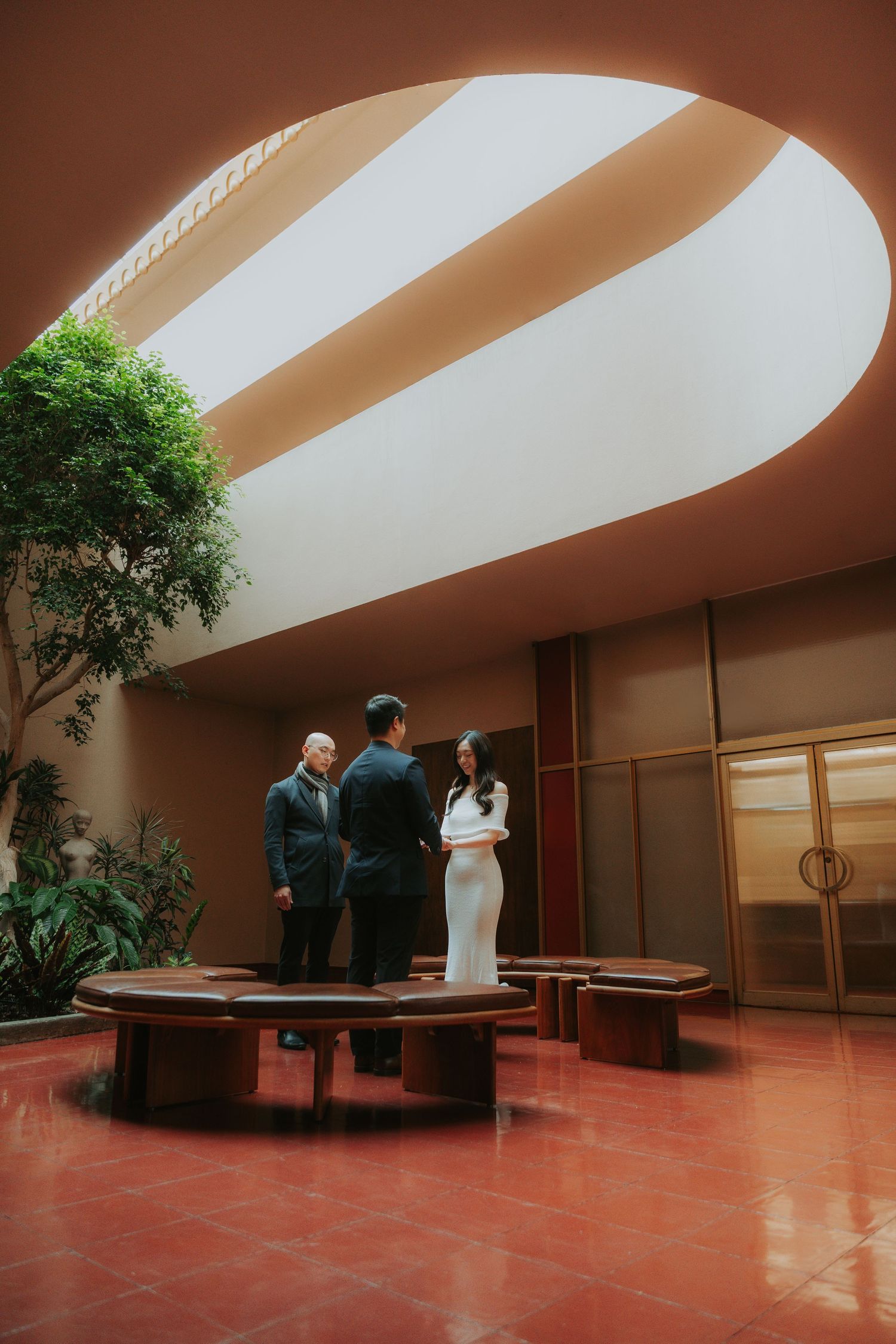 Modern interior space with curved architectural elements and red flooring featuring elegant figures.