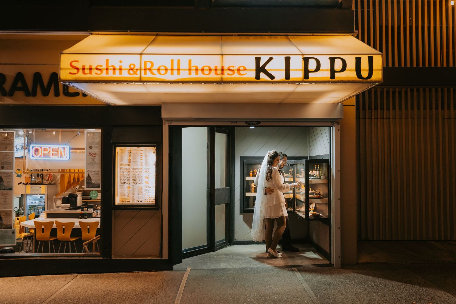 Illuminated storefront of Kippu sushi and roll house restaurant with warm lighting and modern signage at night.