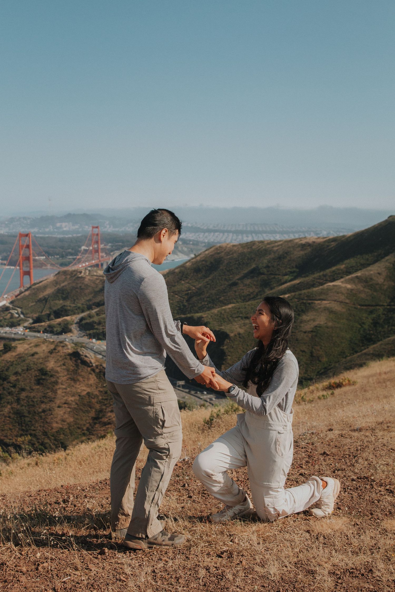 A romantic proposal moment unfolds on a hilltop overlooking the Golden Gate Bridge in San Francisco.