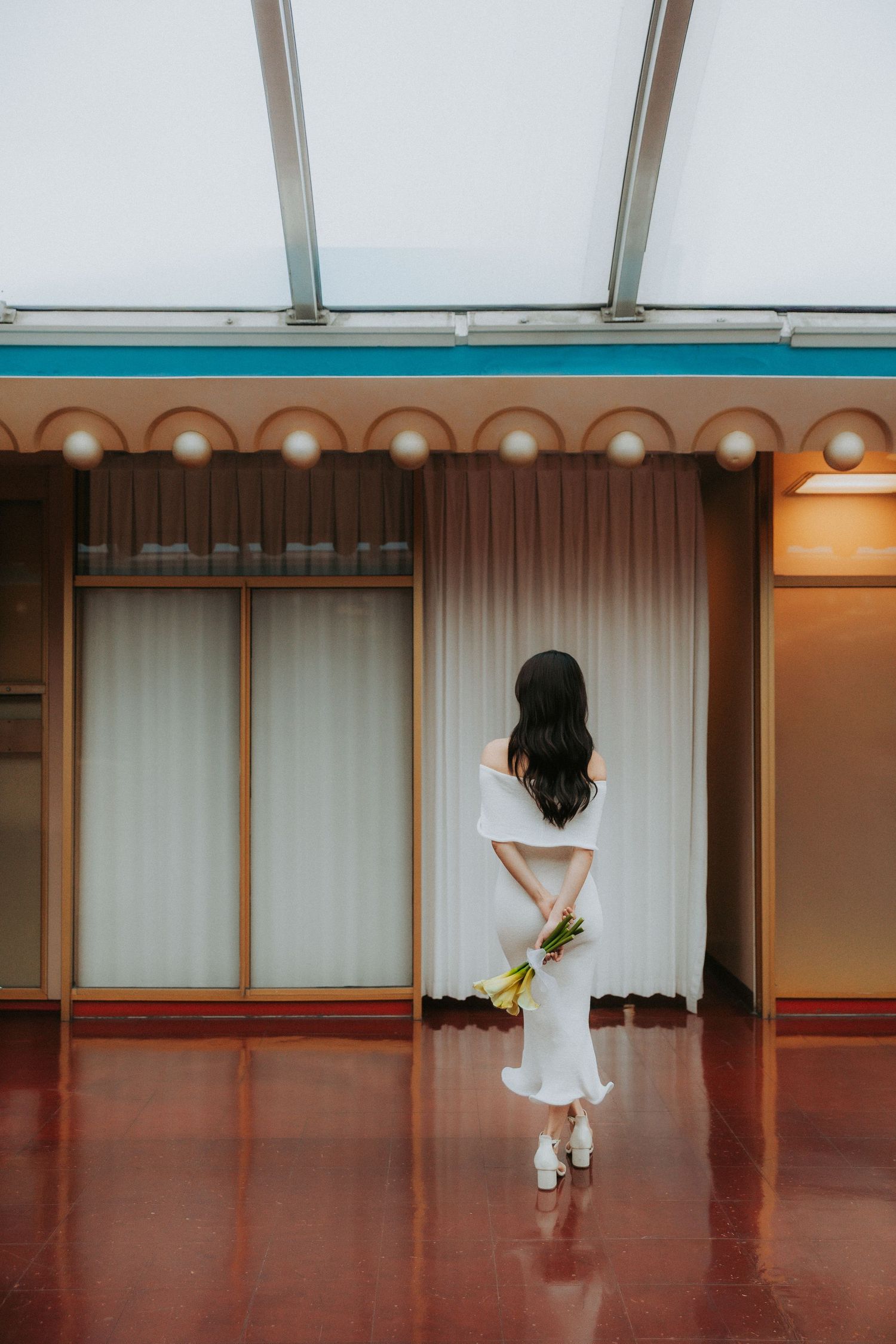 A minimalist dance studio with white curtains and polished wooden floors reflecting soft light.