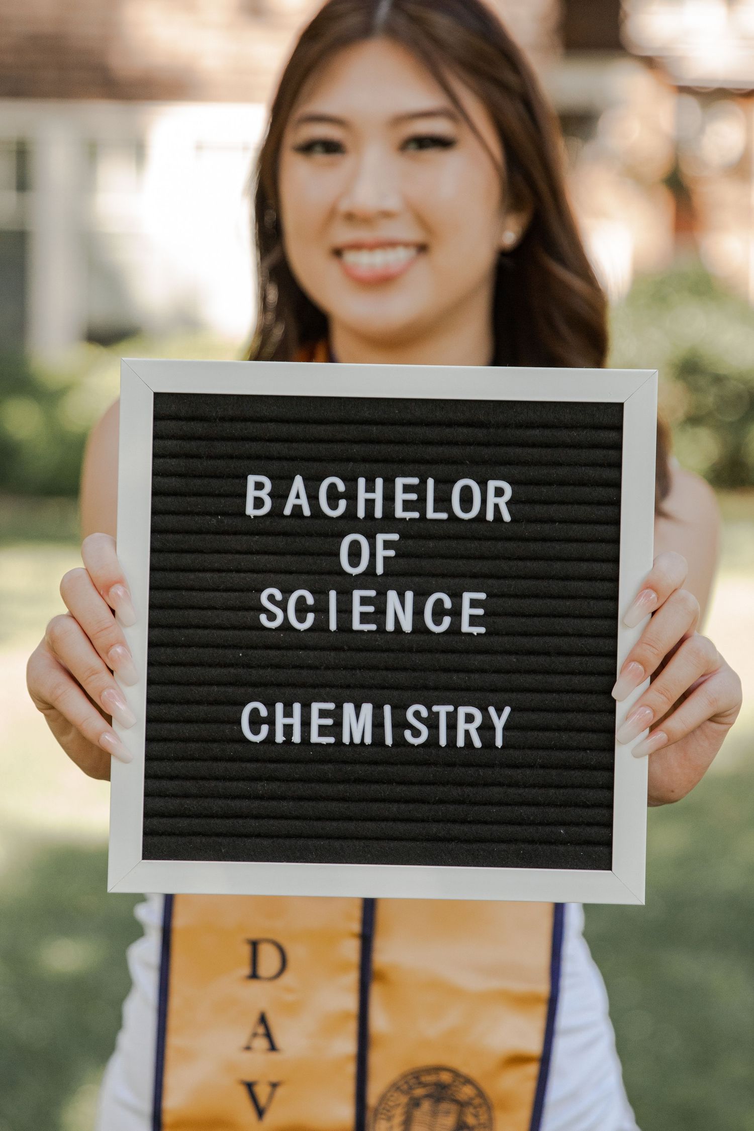 Graduate displays letter board announcing Bachelor of Science in Chemistry degree.
