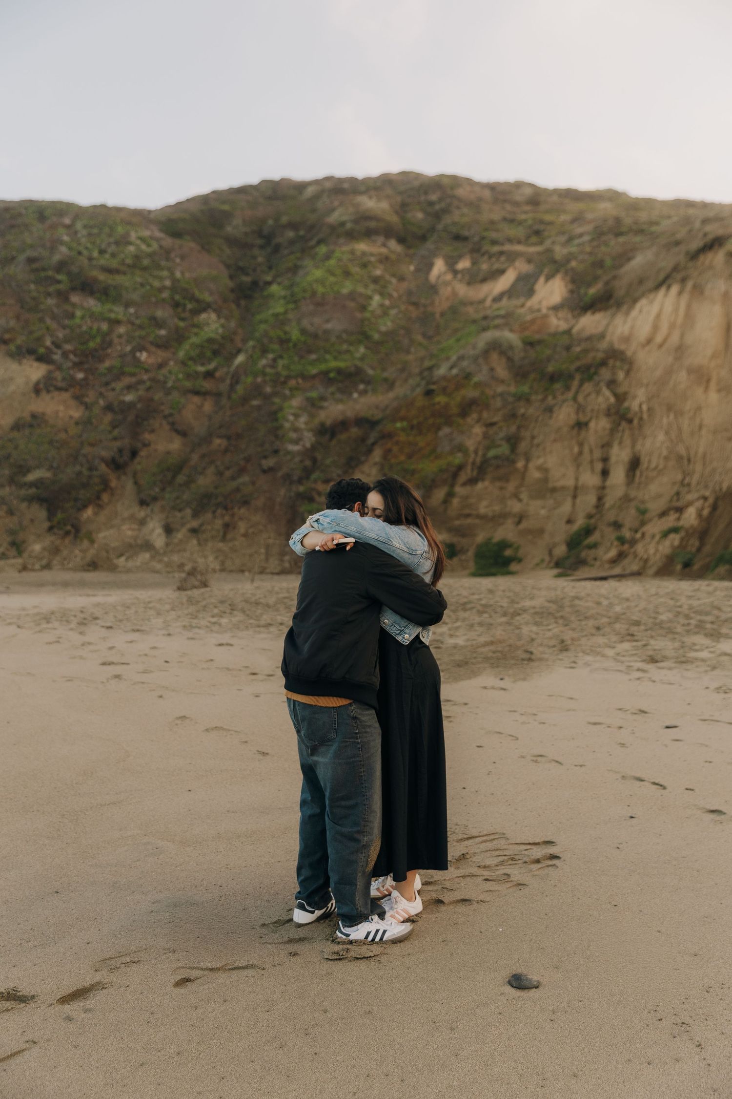 A sequence of photos showing two people embracing on a sandy beach with cliffs in the background.