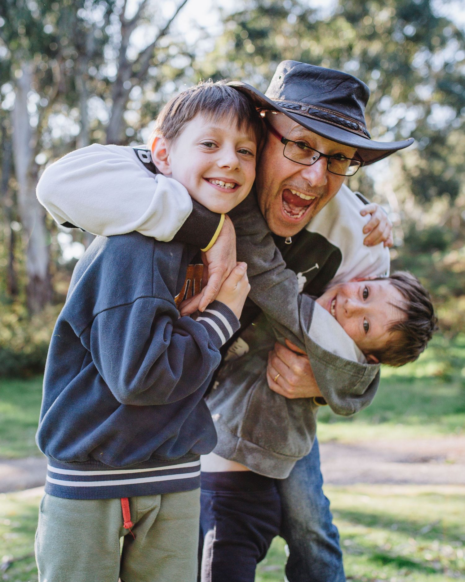 Playful outdoor family moment captured in natural lighting among trees.