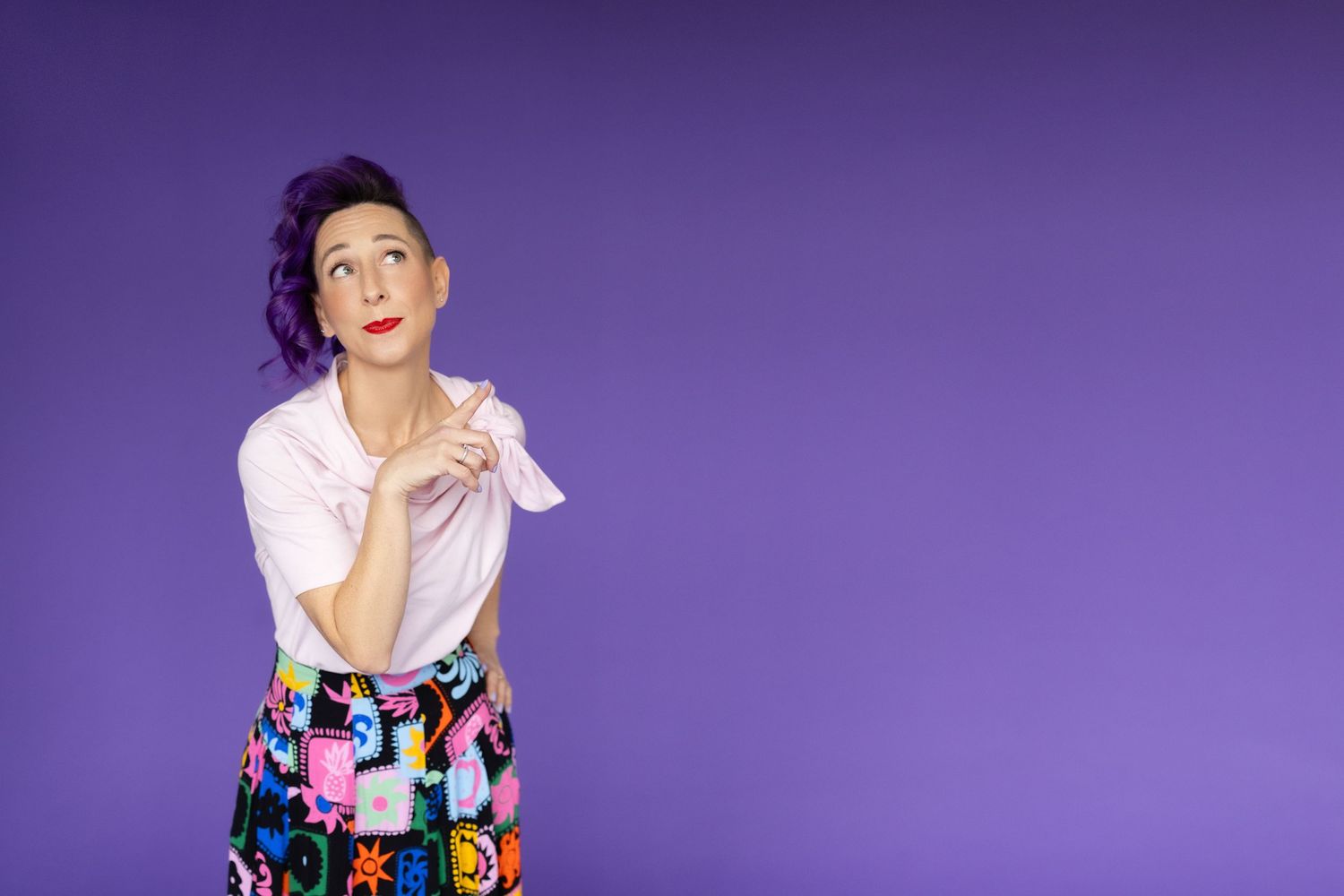 Woman in floral skirt expressing surprise against purple background.