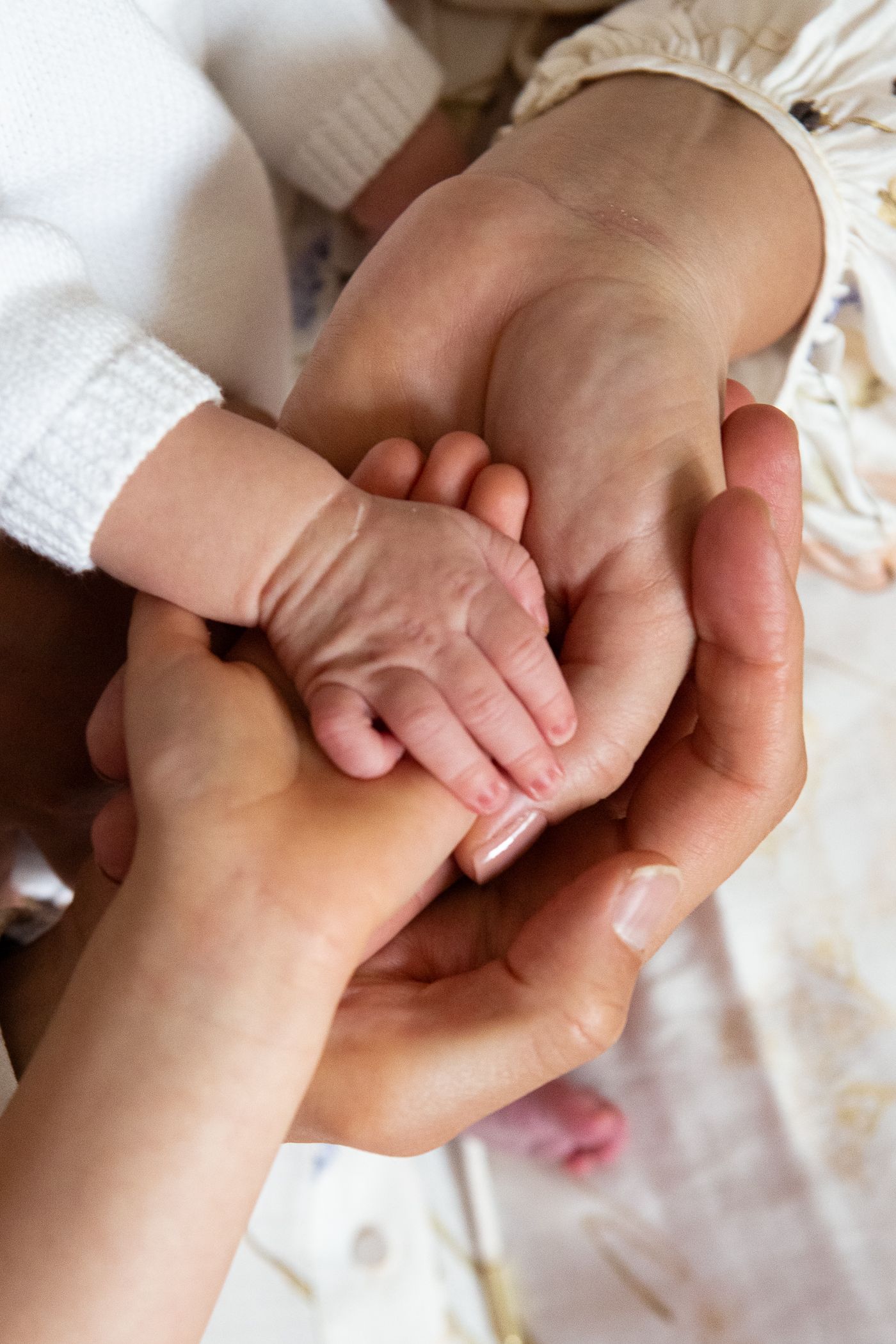 Adult hands gently cradling a tiny newborn baby hand, symbolizing love, protection, and family bond.