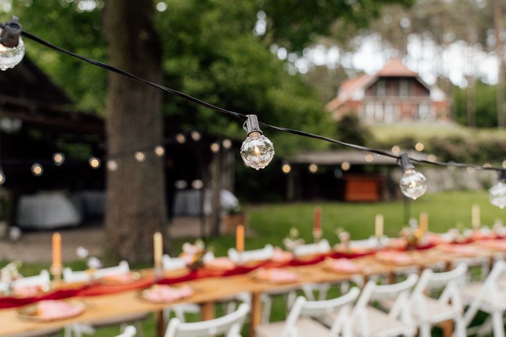 String lights and white canopy tents create an elegant outdoor wedding reception setup in a garden setting.