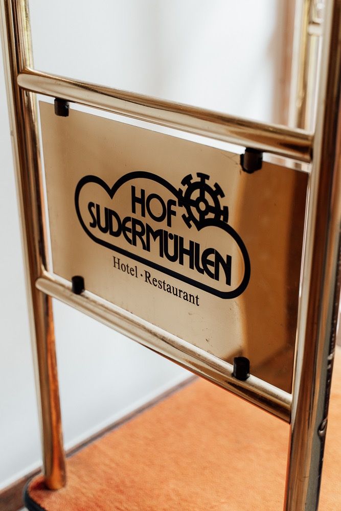Three vintage-style hotel and restaurant signs mounted on a wall with white background and warm lighting.